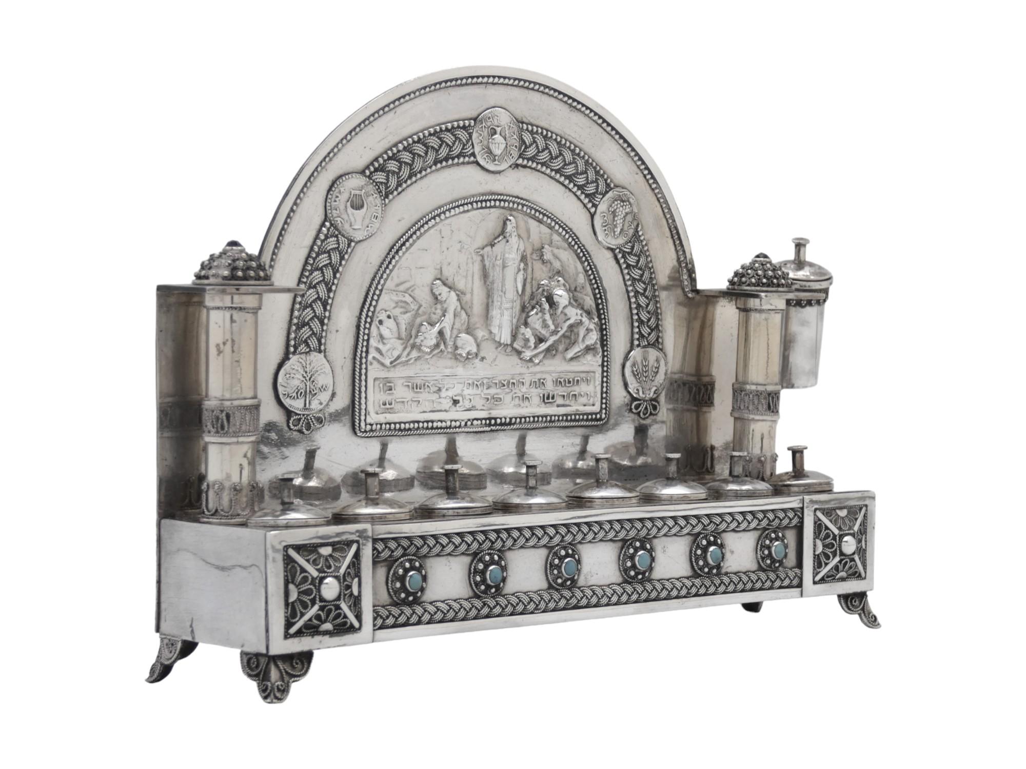 Una lampada di Hanukkah in argento realizzata da Yehia Yemini a Gerusalemme intorno al 1920 è un affascinante pezzo di Judaica. Yehia Yemini era nota per i suoi intricati e dettagliati lavori in argento. Questa lampada presenta disegni elaborati,