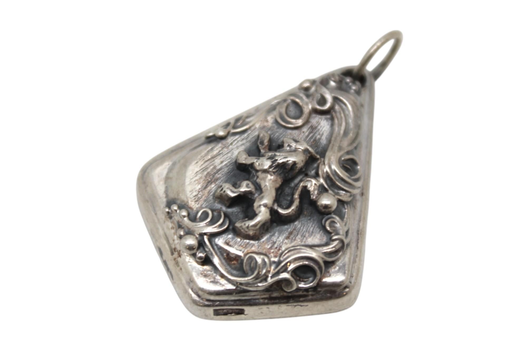 Questo audace ciondolo in argento è realizzato con la tecnica della repousse ed esibisce lo stile caratteristico dell'artista, fatto di rilievi profondamente definiti e ricchezza ornamentale.

Formato da una forma triangolare spessa e a gradini con