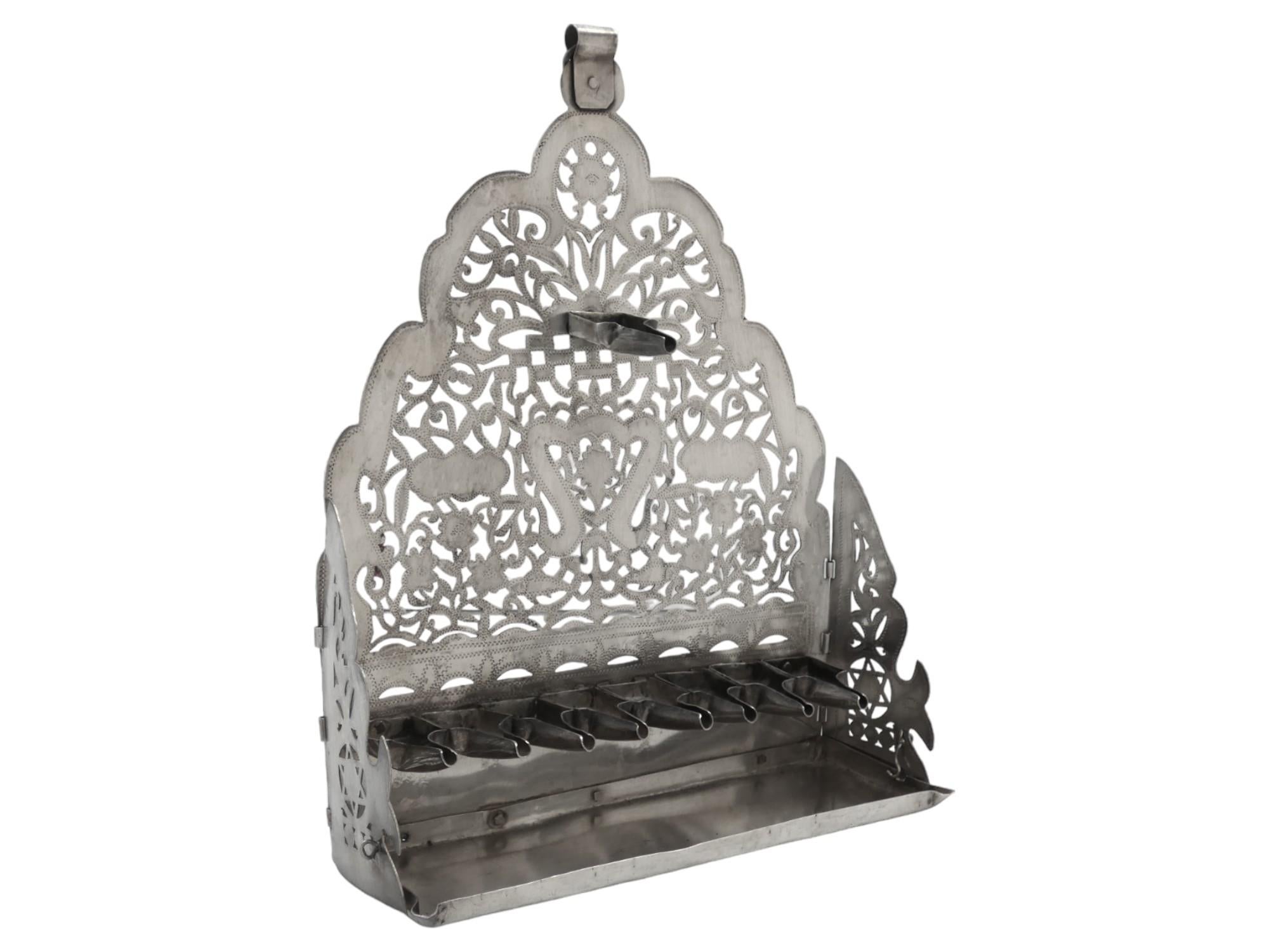 Questa rarissima lampada di Hanukkah nordafricana in argento, risalente al 1900 circa, è un pezzo di Judaica molto notevole, realizzato in argento e con una squisita lavorazione artigianale, che indica che si trattava di un pezzo prezioso e