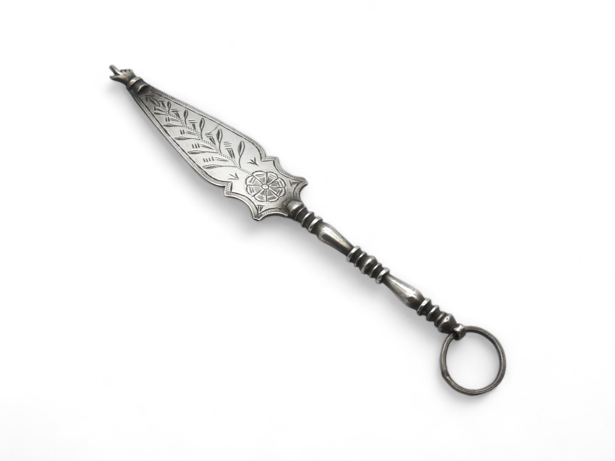 Un elegante puntatore Torah nordafricano in argento, realizzato in Marocco nel 1920 circa.

Sebbene questo puntatore della Torah abbia un design unico e una bella forma e incisione, presenta anche un'interessante Dedic sulla parte superiore del