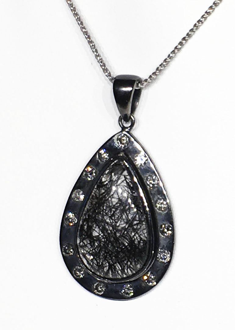 A Silver Pendant with Diamond & Quartz with Graphite Needles - Graphitite.
This Pendant features a central Pear shaped Graphitite Cabochon (Quartz with Graphite Needles) of 27 Carats, surrounded by 15 Round Diamonds which are SI quality and Tinted