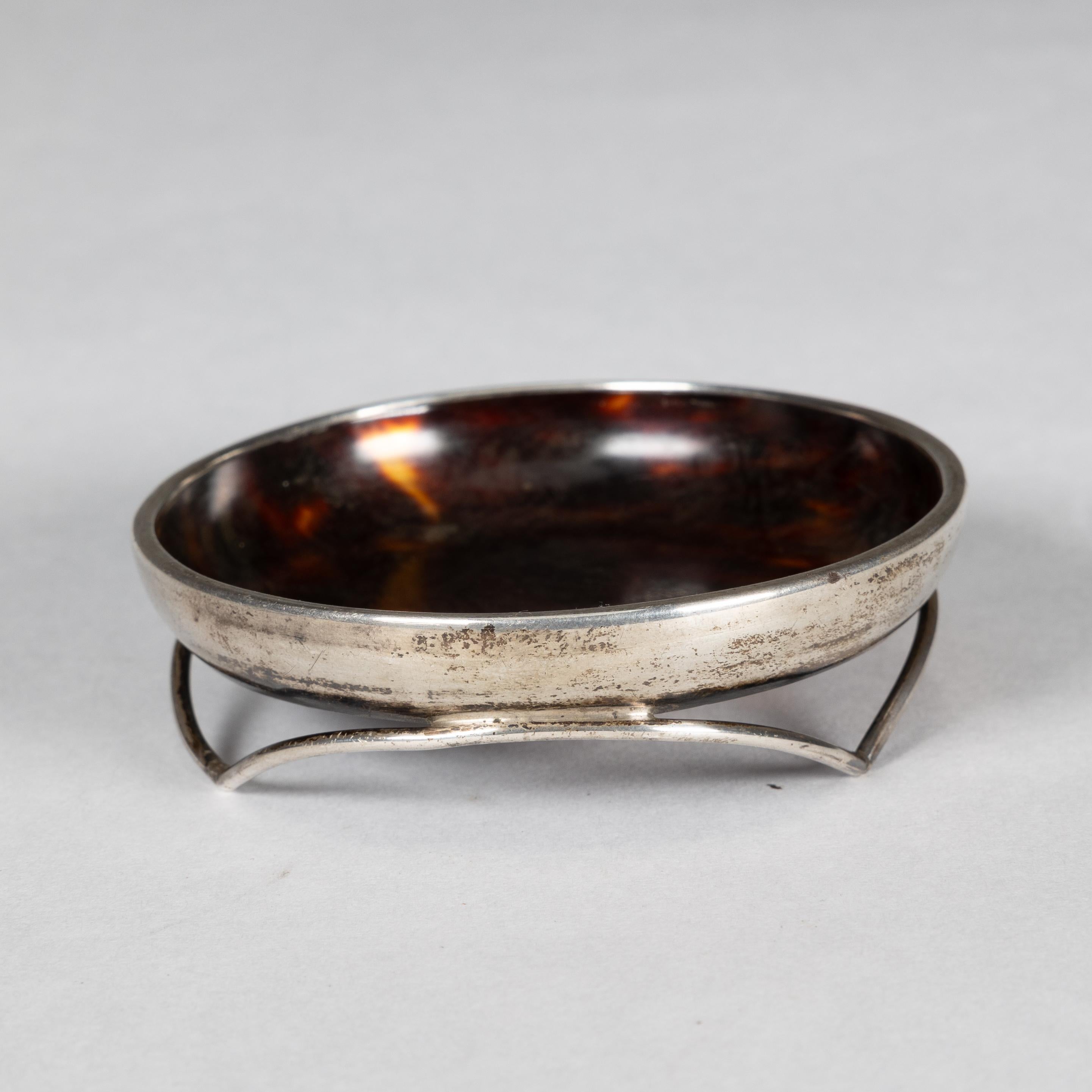 Silver pin dish with a bakelite centre. The makers marks are worn but retains the Anchor mark for Birmingham. There are two small burn holes to the centre.