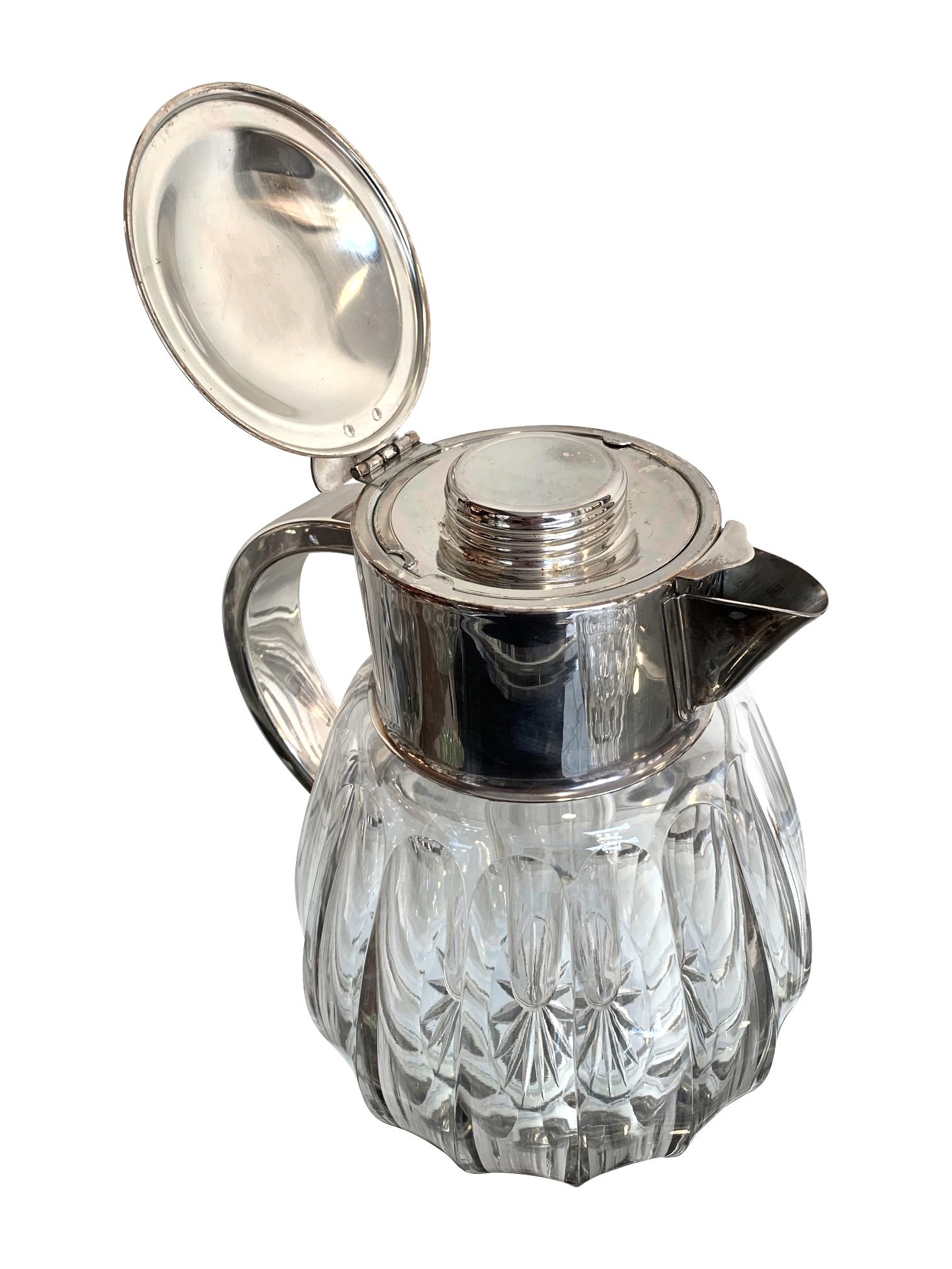 An English silver plated faceted crystal lemonade / cocktail jug with hinged silver plated lid and handle that opens to reveal the central glass ice compartment. The pourer has a removable strainer.
