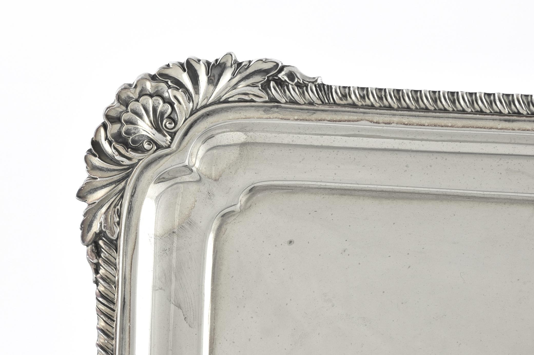 This silver plated tray was crafted in England. Whilst the base of this try is plain, the boarders are beautifully embellished with shell and gadroon. The exterior of the tray is marked ' CF & Co' for the maker.