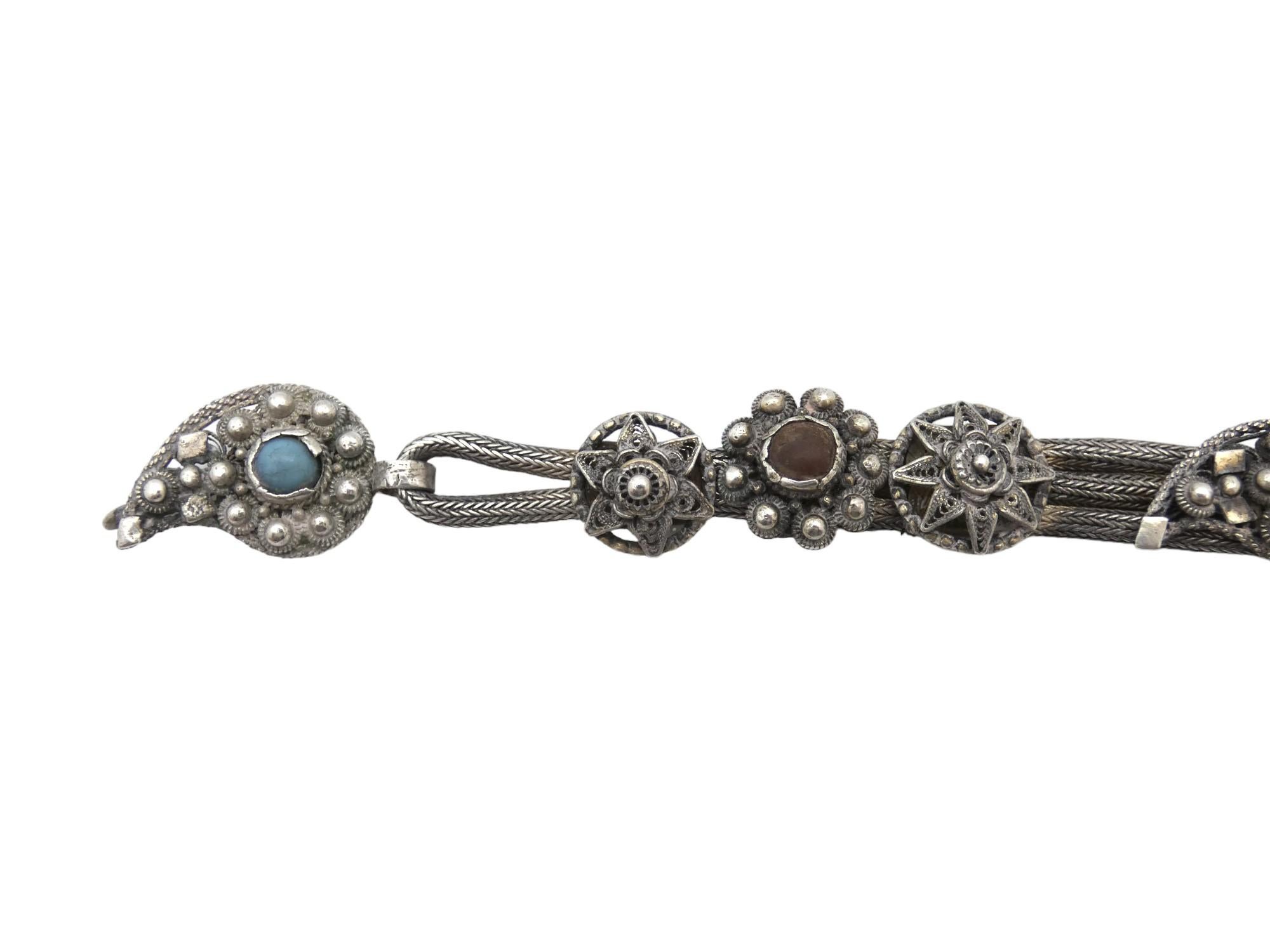 Questo bracciale d'argento con corda e medaglioni, realizzato intorno al 1900, è un esempio distintivo e finemente lavorato di gioielleria yemenita, che si discosta dalle forme tradizionali a fascia piena. Invece, la struttura centrale del bracciale