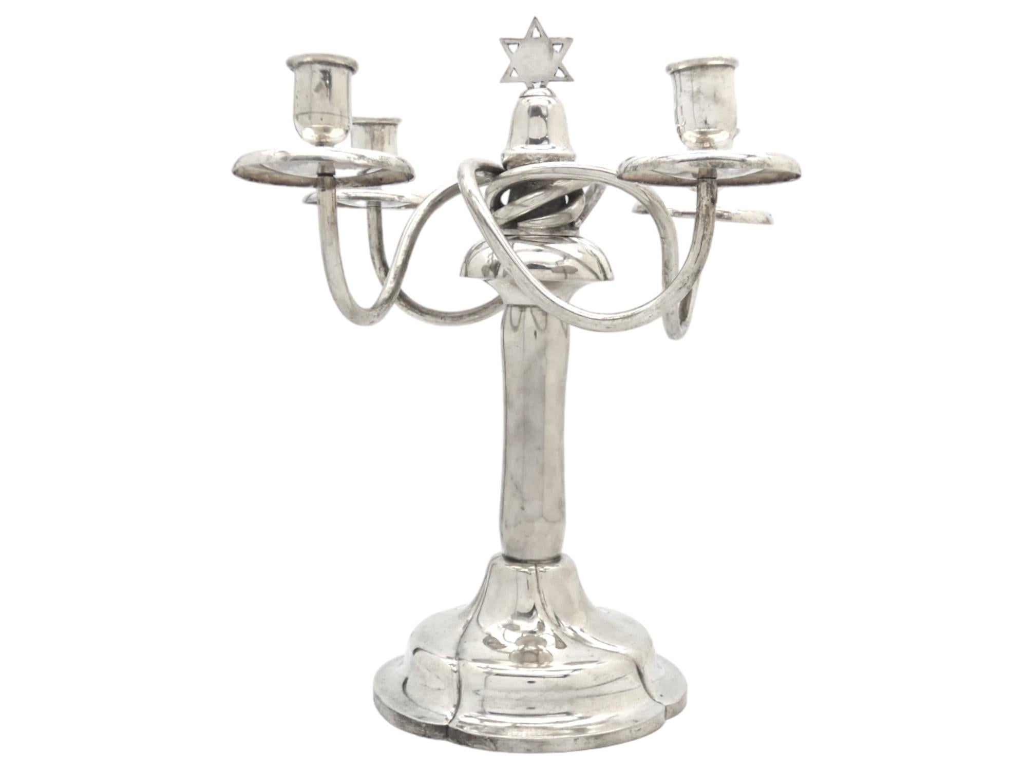 Un elegante candelabro da Shabbat in argento proveniente dall'Austria, risalente al 1925 circa, è un pezzo impressionante di Judaica, che fonde il patrimonio culturale e artistico delle tradizioni ebraiche con l'abilità artigianale degli argentieri