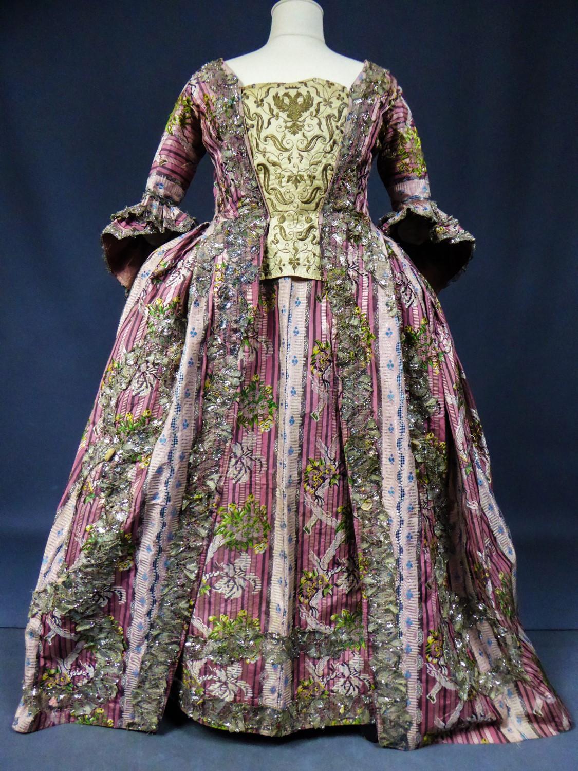 Circa 1765/1780
France-Paris Versailles

French court dress in silver flossed, fluted and brocaded silk or brocade. Coat open on a stomacher (sold separatly) and three-quarter sleeves with double rows of pagoda ruffles. Back with box pleats said 