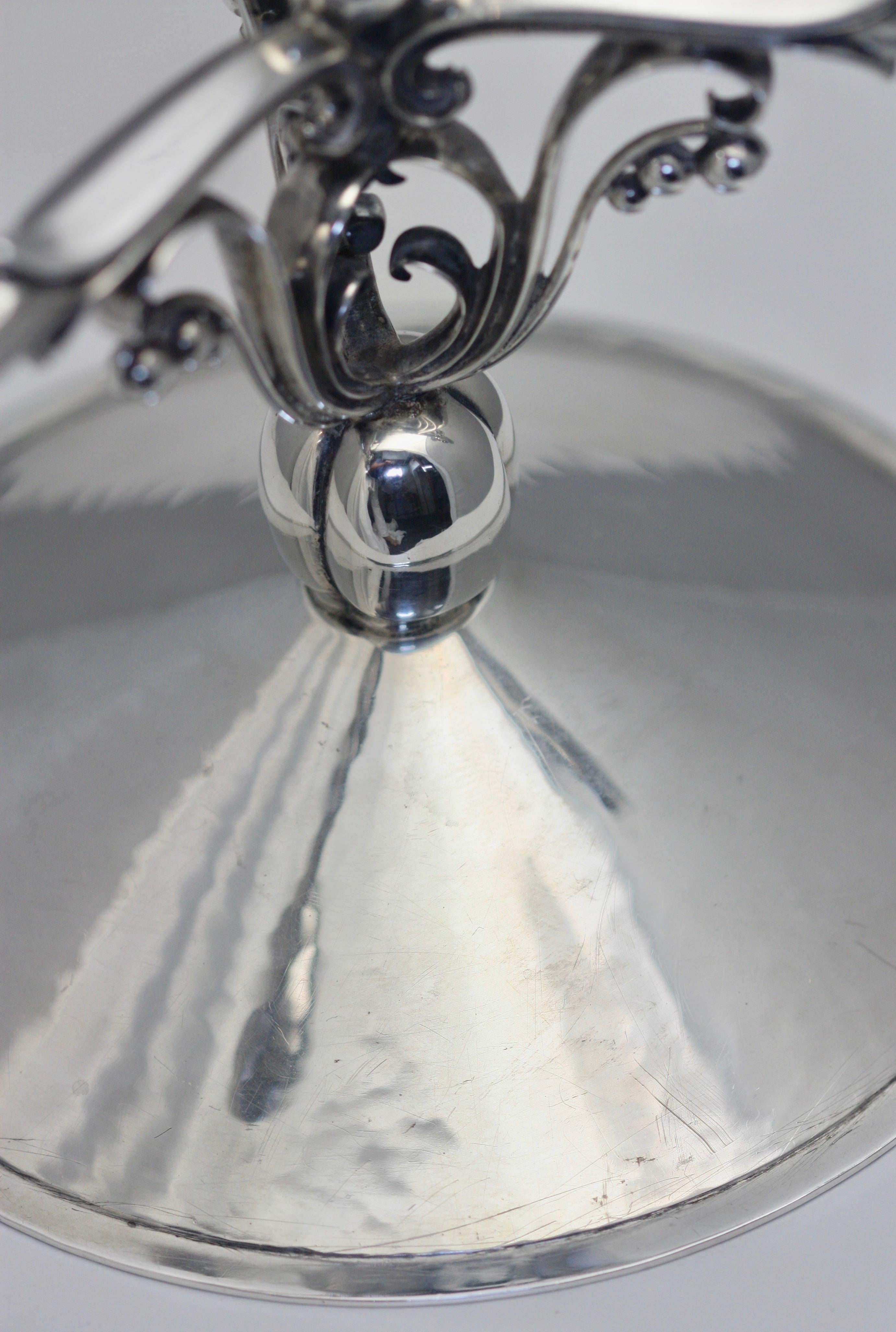 Candelabro a tre luci in argento un candelabro a tre luci in argento, marchio di max Rieg, Williamsburg, circa 1940. Su una base circolare a cupola, di gusto danese, lo stendardo centrale traforato con foglie e bacche, che sostiene tre rami reeder