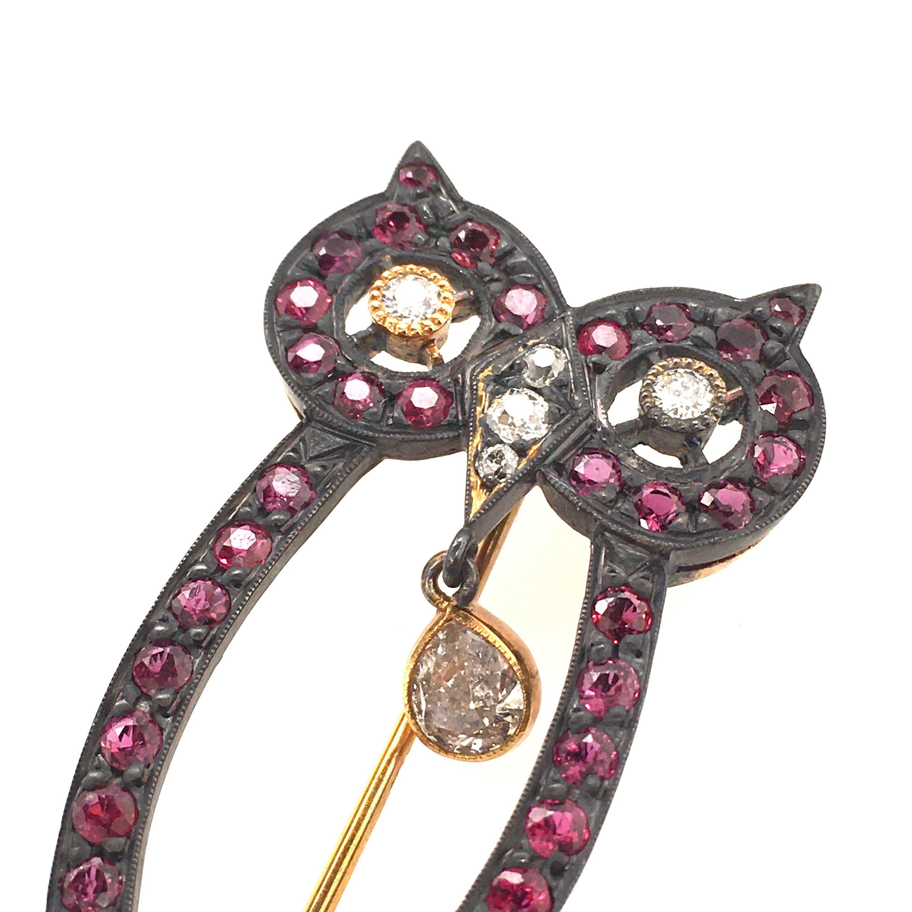 A 14 karat yellow gold, silver topped, ruby and diamond owl brooch. Designed as  a pave set ruby openwork owl, enhanced by circular cut diamonds, suspending a pear shaped diamond, weighing approximately 0.25 carat. Length is approximately 1 3/4