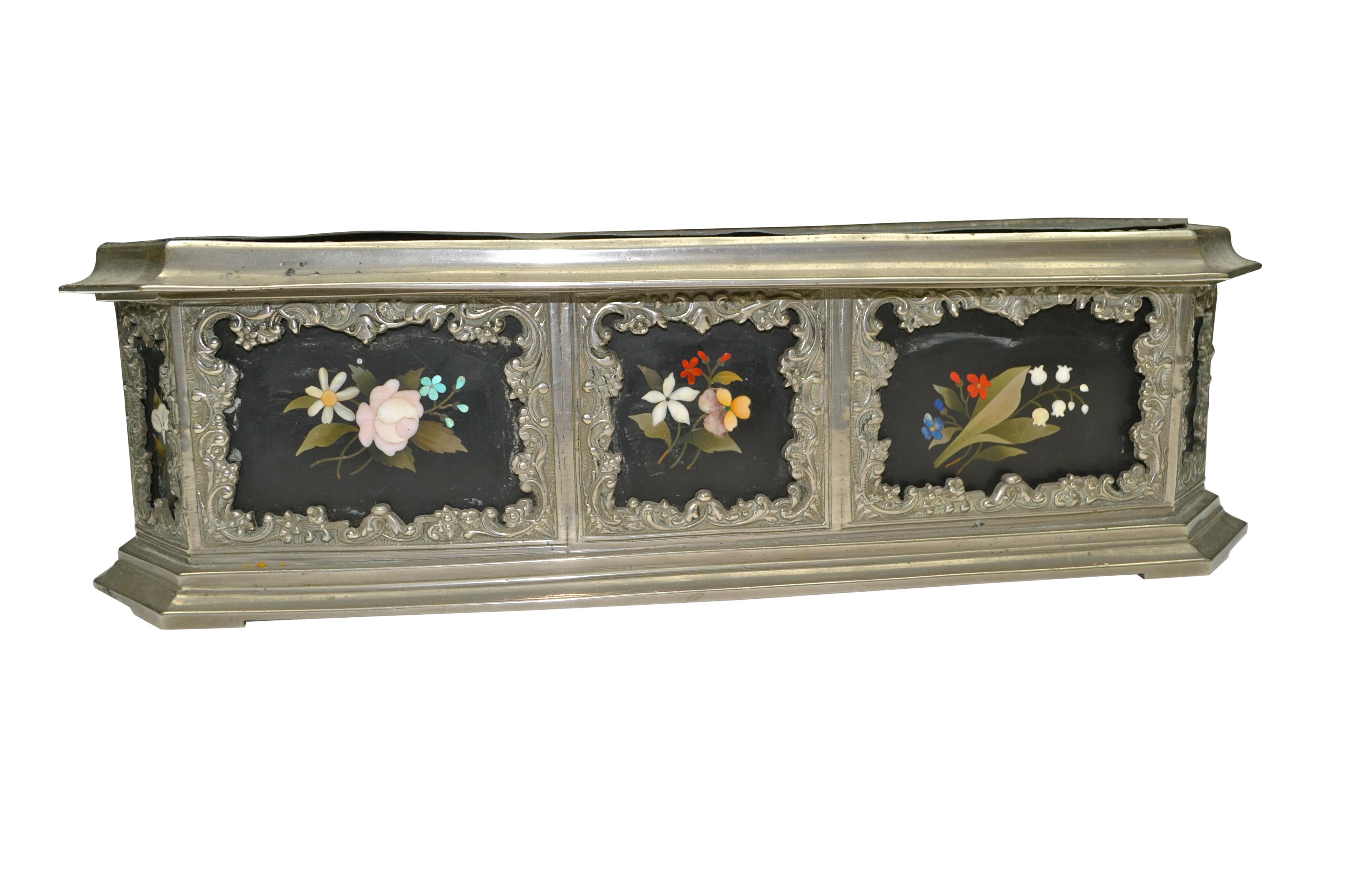 A rare silvered metal desk or tabletop planter inlaid with 12 framed Pietra Dura panels of inlaid colorful flowers on a black base, complete with its original lead liner.
     