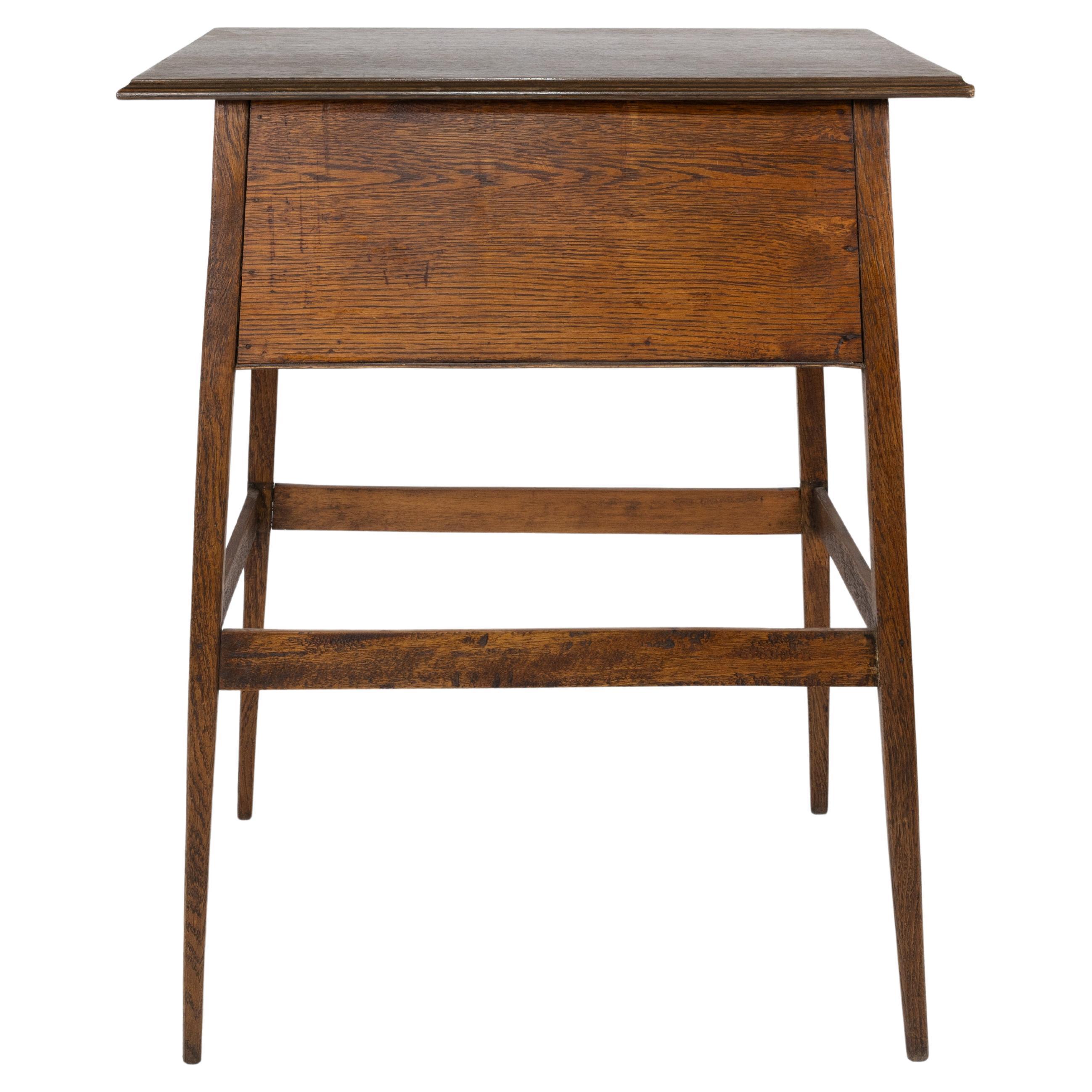 A simple Arts and Crafts oak oblong side or bedside table with a moulded edge to the top and a usful storage cuboard below on slender tapering legs united by lower stretchers.
