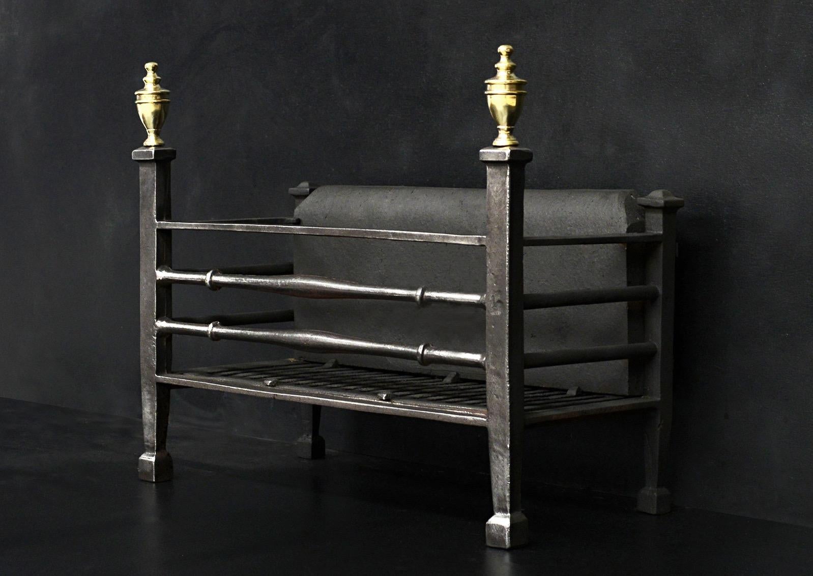 A simple polished steel firegrate. The tapering legs surmounted by brass urn finials. The burning area with shaped front bars and plain back behind. English, 20th century. 

Measures: Width at front: 570 mm 22 ½