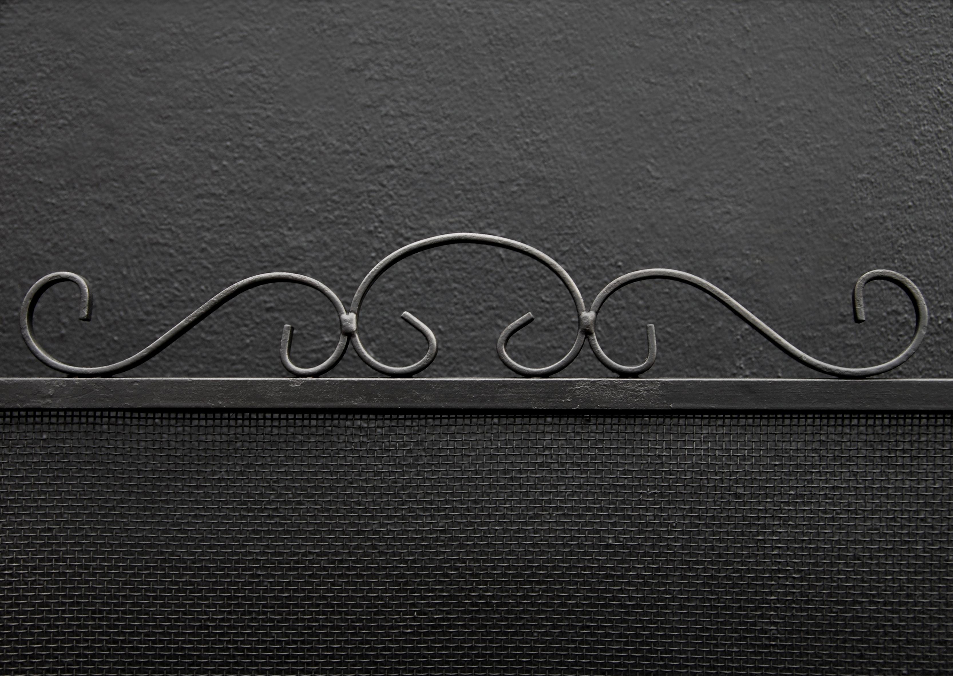 A simple wrought iron firescreen with decorative scrolled handle and feet. Fine black mesh behind.

Height:	730 mm      	28 ¾