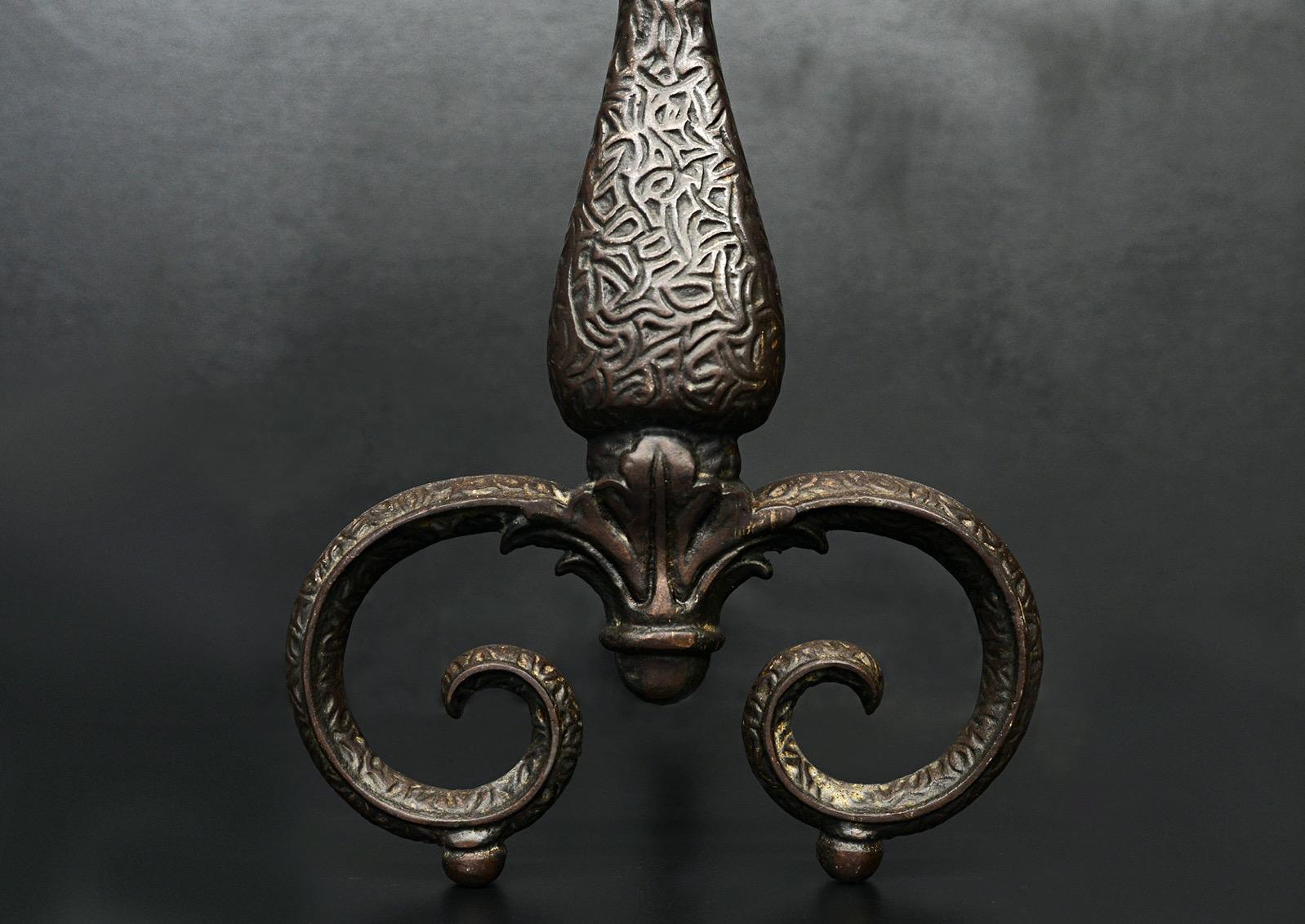 A decorative pair of iron firedogs. The engraved scrolled feet surmounted by tapering uprights with finials above. Currently with a brown wax finish, but could be polished if required. English, circa 1900. 

Height:	540 mm      	21 ¼