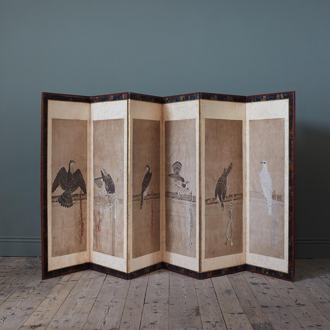 A Single Late 19th Century Six Panel Paper Screen, depicting Tethered Hawks, in the manner of Soga Chokuan 

Combined twelve gouache painted scenes of tethered hawks, laid down to form this six panel screen, with pigment and ink on rice paper,