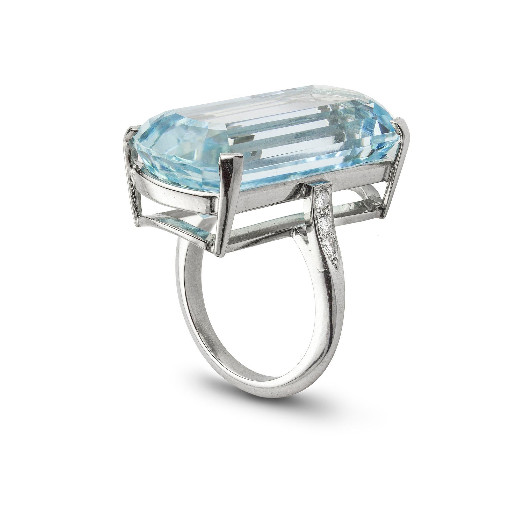 A single stone aquamarine ring, the rounded end rectangular shape, step-cut aquamarine measuring approximately28x14x11mm and weighing 28.39 carats, four claw set in platinum mount with three round brilliant-cut diamond set to each lift-up shoulder,