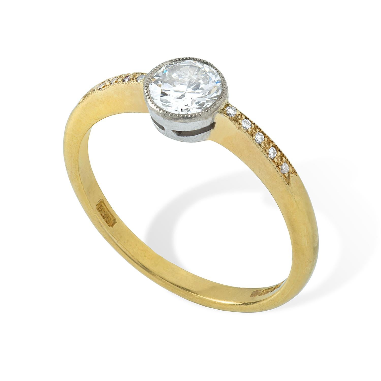 A single stone diamond ring, the round brilliant-cut diamond weighing 0.56 carats, assessed colour I, assessed clarity SI2, millegrain-set in a platinum collet, all to a yellow gold tapered shank with diamond millegrain-set shoulders, hallmarked