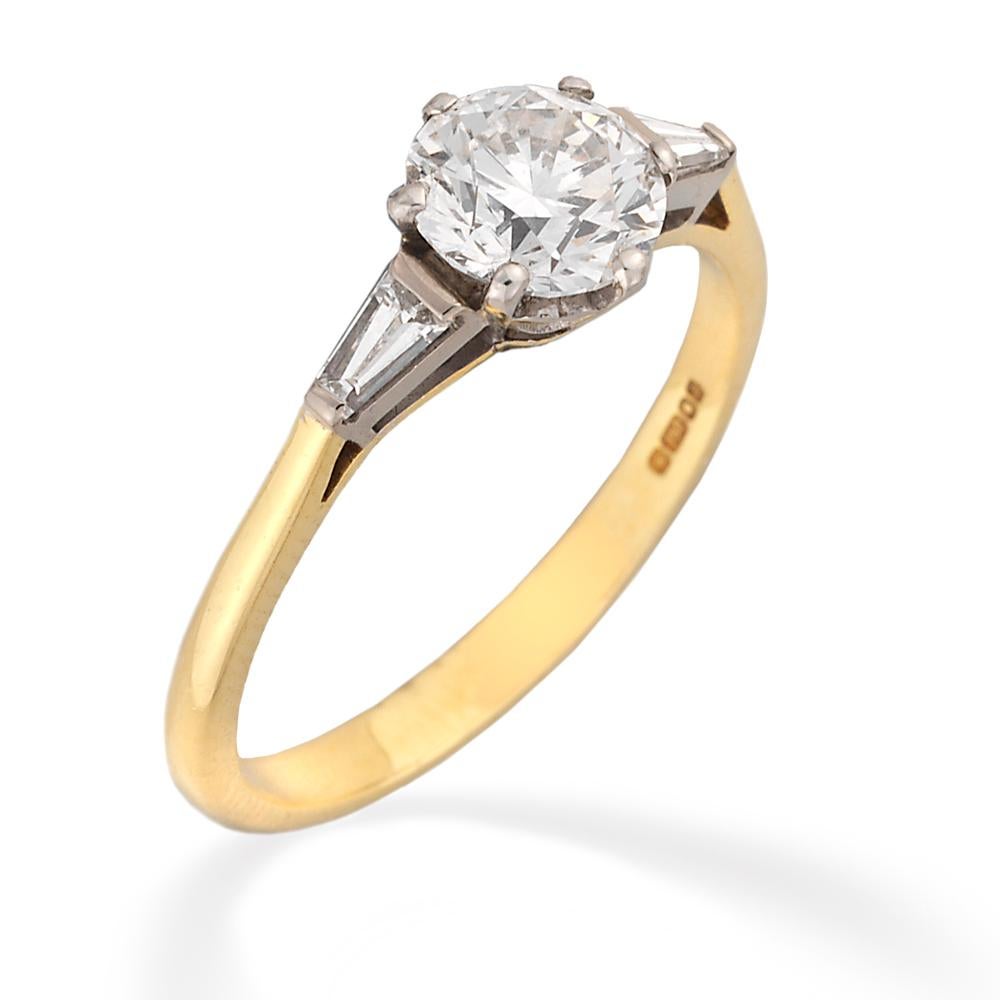 A single stone diamond ring, the ring set with a round brilliant-cut diamond, weighing 1.03 carats of F colour VVS1 clarity with GIA certificate , set to an heart-shape platinum collet with baguette-cut diamond shoulders and 18 carats yellow