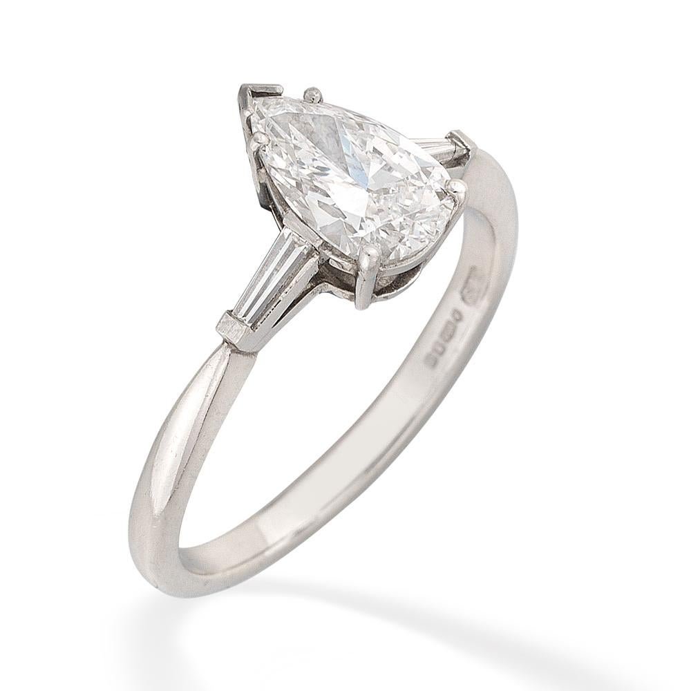 A single stone diamond ring, the pear-shaped diamond weighing 1.06 carats,accompanied by AnchorCert gemmological office London, certificate stating to be of E colour, VVS2 clarity, claw-set to a platinum mount with tapered baguette-cut shoulders and