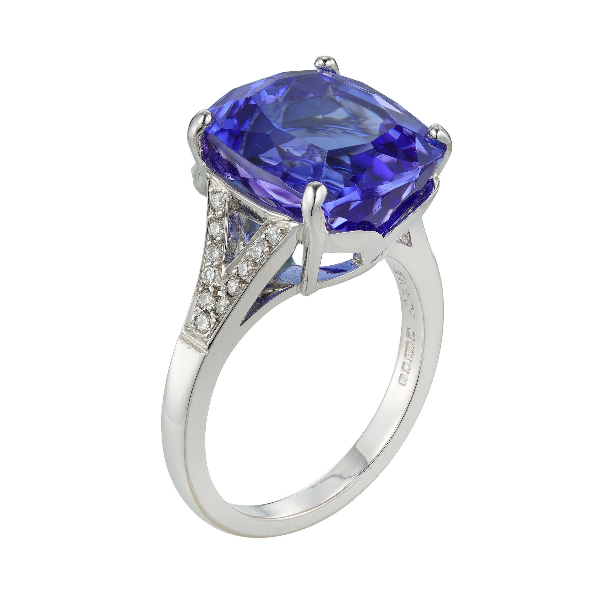 A single stone tanzanite ring, the cushion-cut tanzanite weighing 9.77 carats, four claw-set between split shoulders set with small round brilliant-cut diamonds weighing 0.19 carats in total, all mounted in white gold with square/section shank,