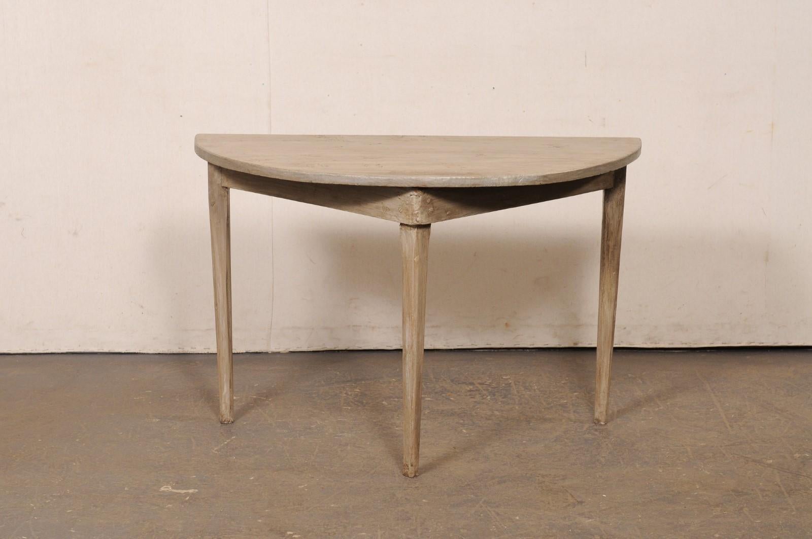 Une table demi-lune suédoise en bois peint du début du 20e siècle. Cette table ancienne de Suède, datant des années 1930, présente un plateau semi-circulaire surmonté d'un tablier simple de forme triangulaire, et repose sur trois pieds carrés et
