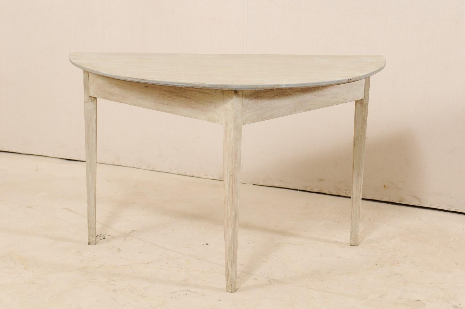 A 19th century Swedish painted wood demilune table. This antique demilune table from Sweden, circa 1880s, features a semi-circular top over a plain, triangular-shaped apron. This table is raised upon three squared legs which gently taper towards