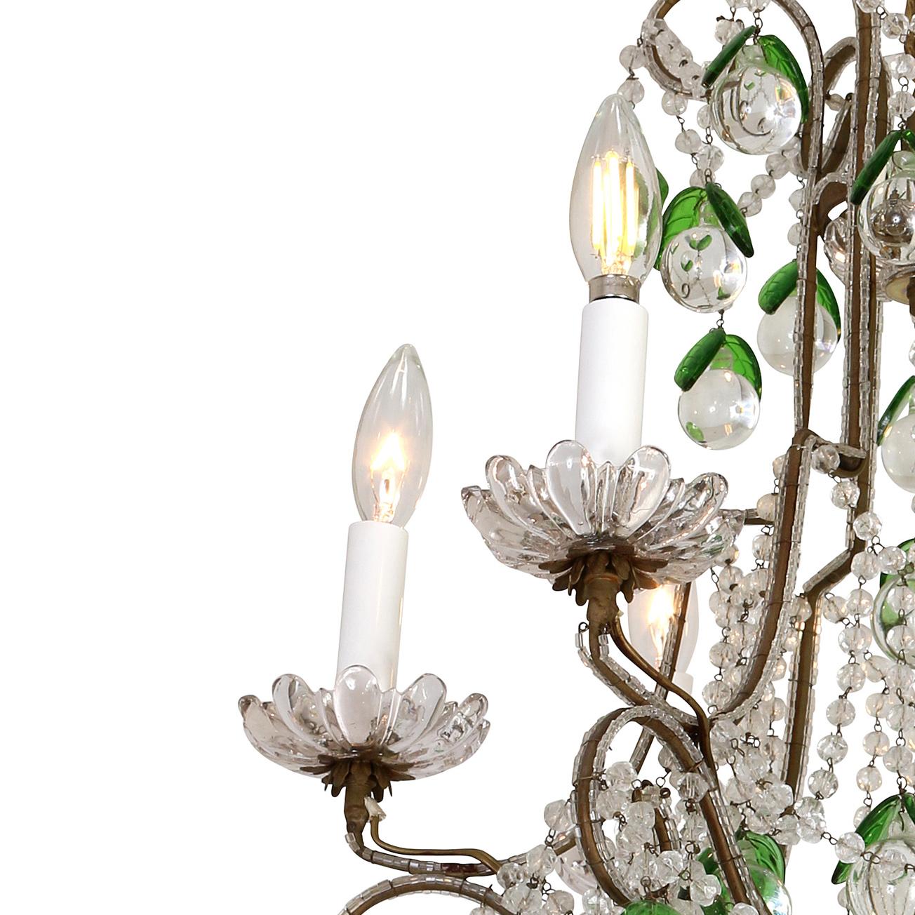 This fanciful crystal and iron chandelier is composed of six arms with lovely floral bobeches.  The silvered iron frame is decorated with crystal balls and beads, accented with green glass leaves.  The medium size of this piece makes it quite