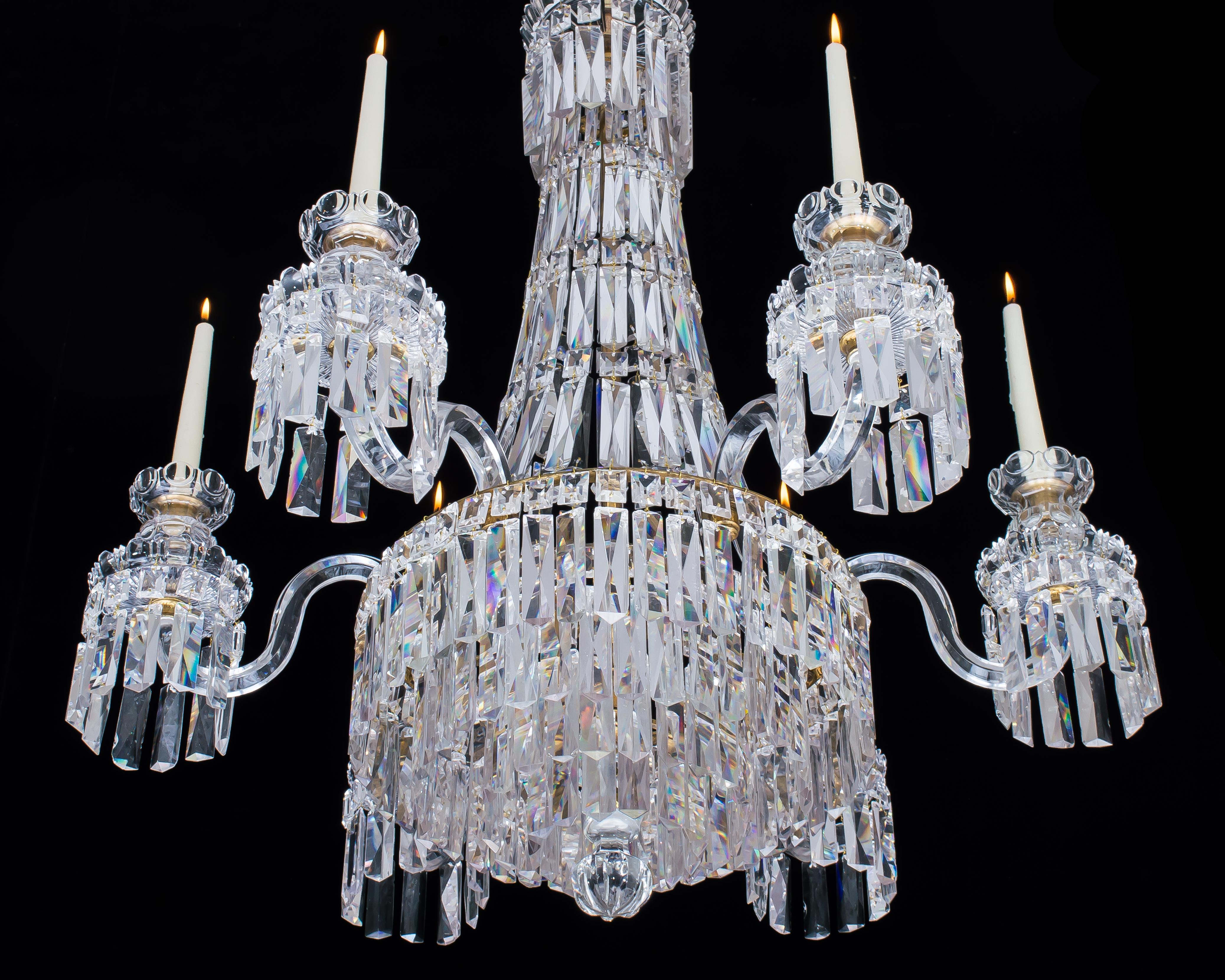 A William IV chandelier of Classic tent and waterfall design, from the drop hung corona the graduated chains Cascade to the main ring issuing six sided arms supporting radial cut drip pans and most unusual candle nozzles with convex and concave