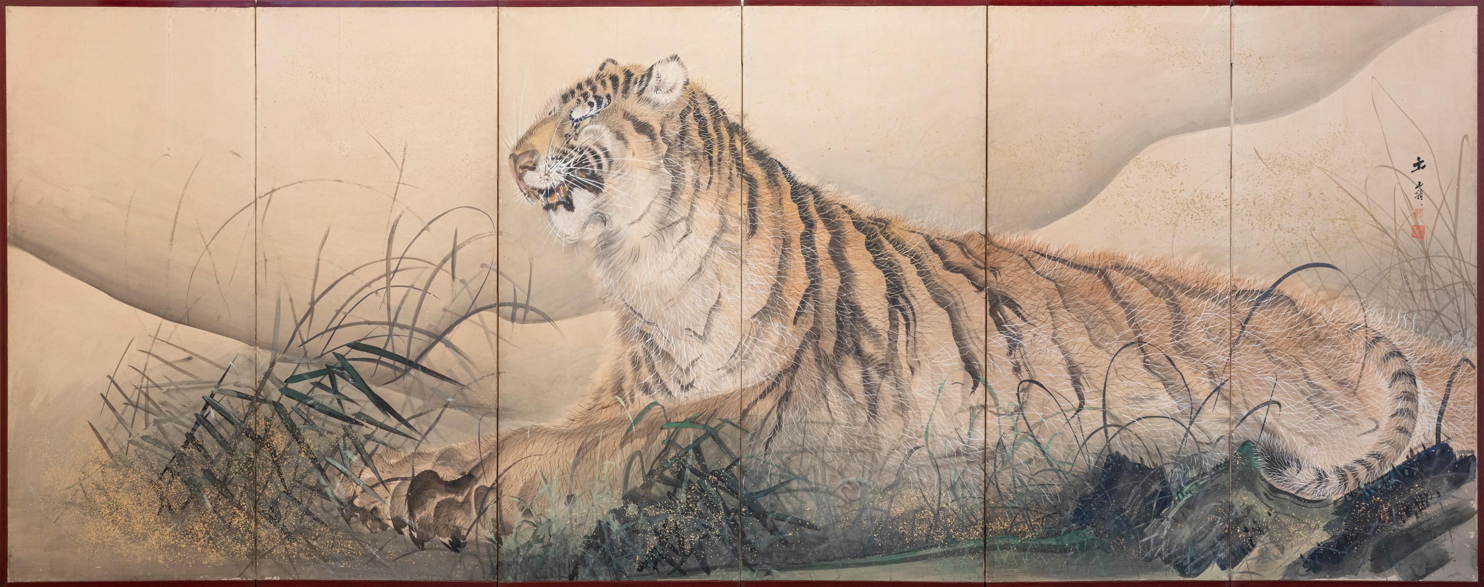 Ein japanischer Sechspaneelschirm, der mit Goldpulver auf Papier gemalt ist und einen majestätischen Tiger zeigt, der im hohen Gras liegt und sich kraftvoll aus der leicht angedeuteten Landschaft im Hintergrund erhebt.

Das Tier wird mit großer