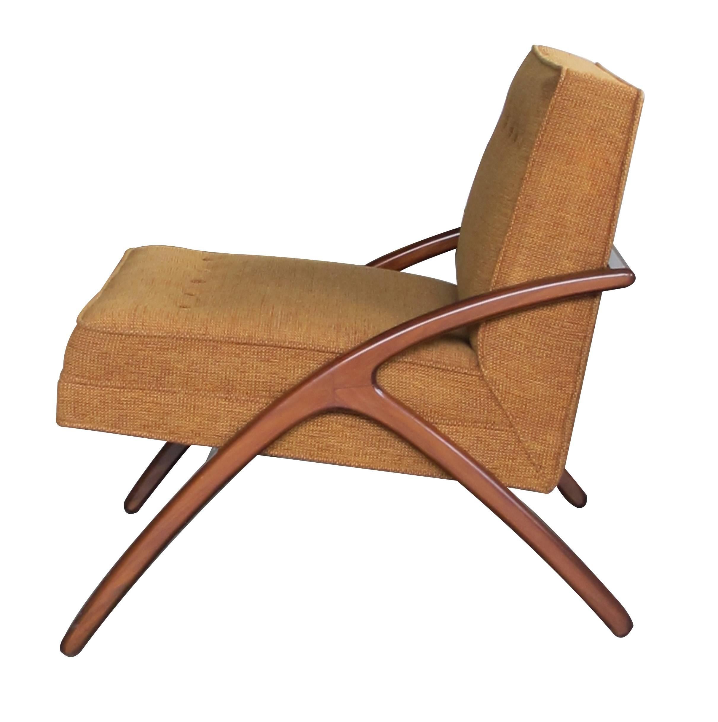 With elegant lines, each chair with upholstered back and seat resting on a graceful wooden frame with arching legs joined at the back; with splayed legs at the rear.