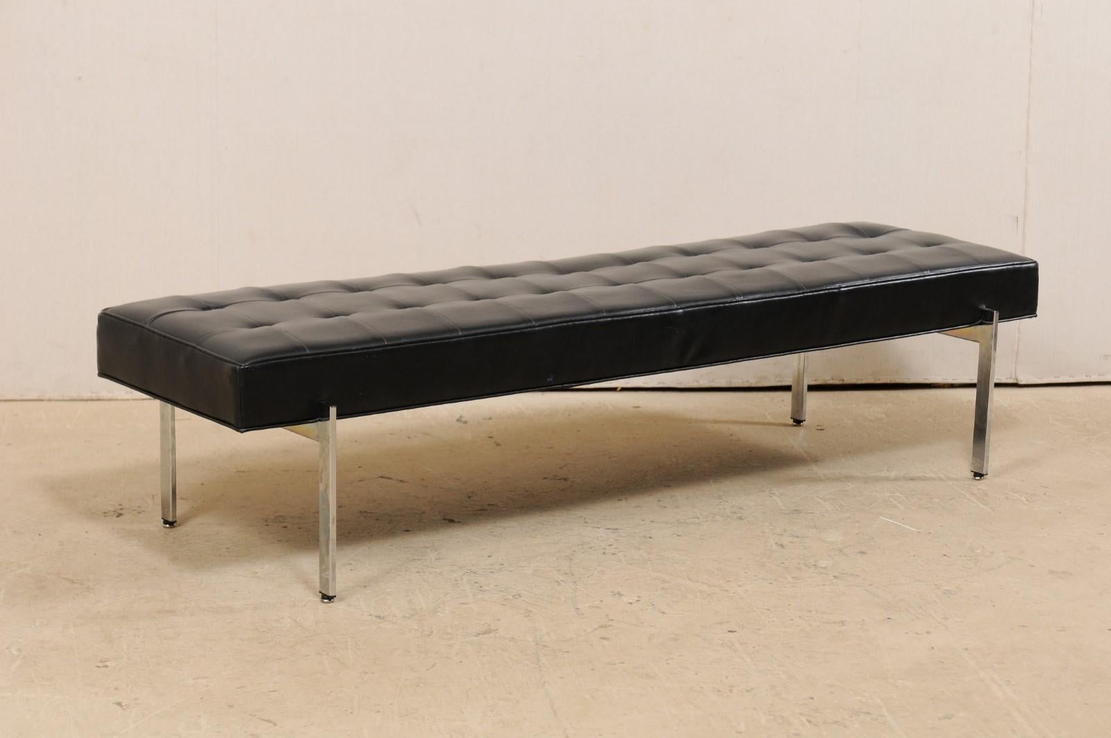 A vintage bench designed by Milo Baughman for The Thayer Coggin Institutional, Inc. (High Point, NC). This backless bench has been designed in very modern, minimal lines; the rectangular-shaped seat is covered in tufted black leather, and is raised