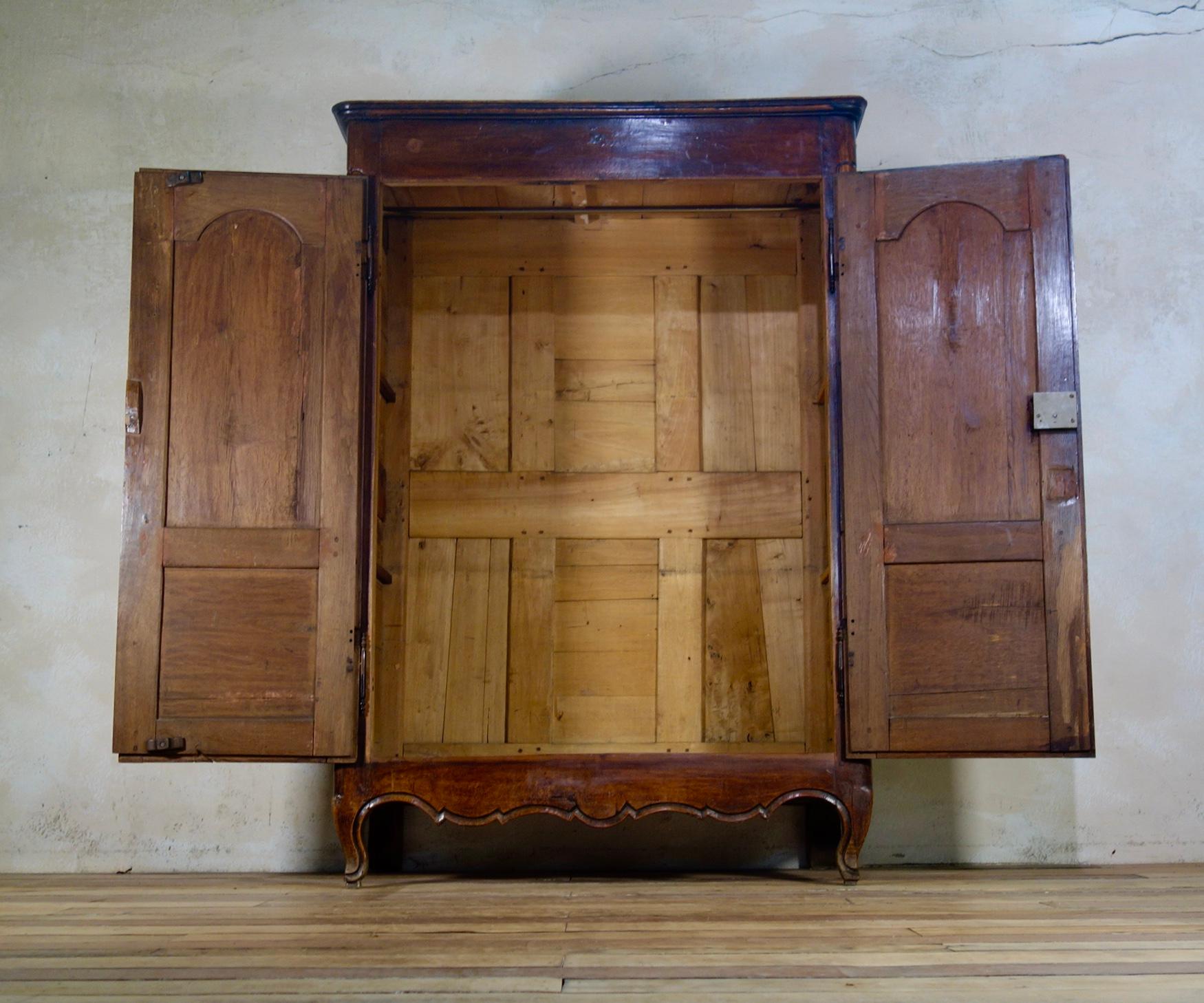 A small 18th century Provincial oak armoire, demonstrating a striking patination with a rich and warm luster. 
Featuring a simple rounded cornice above a pair of arched paneled doors, raised on scrolling feet. 
 
Measures: Height 166cm
Width