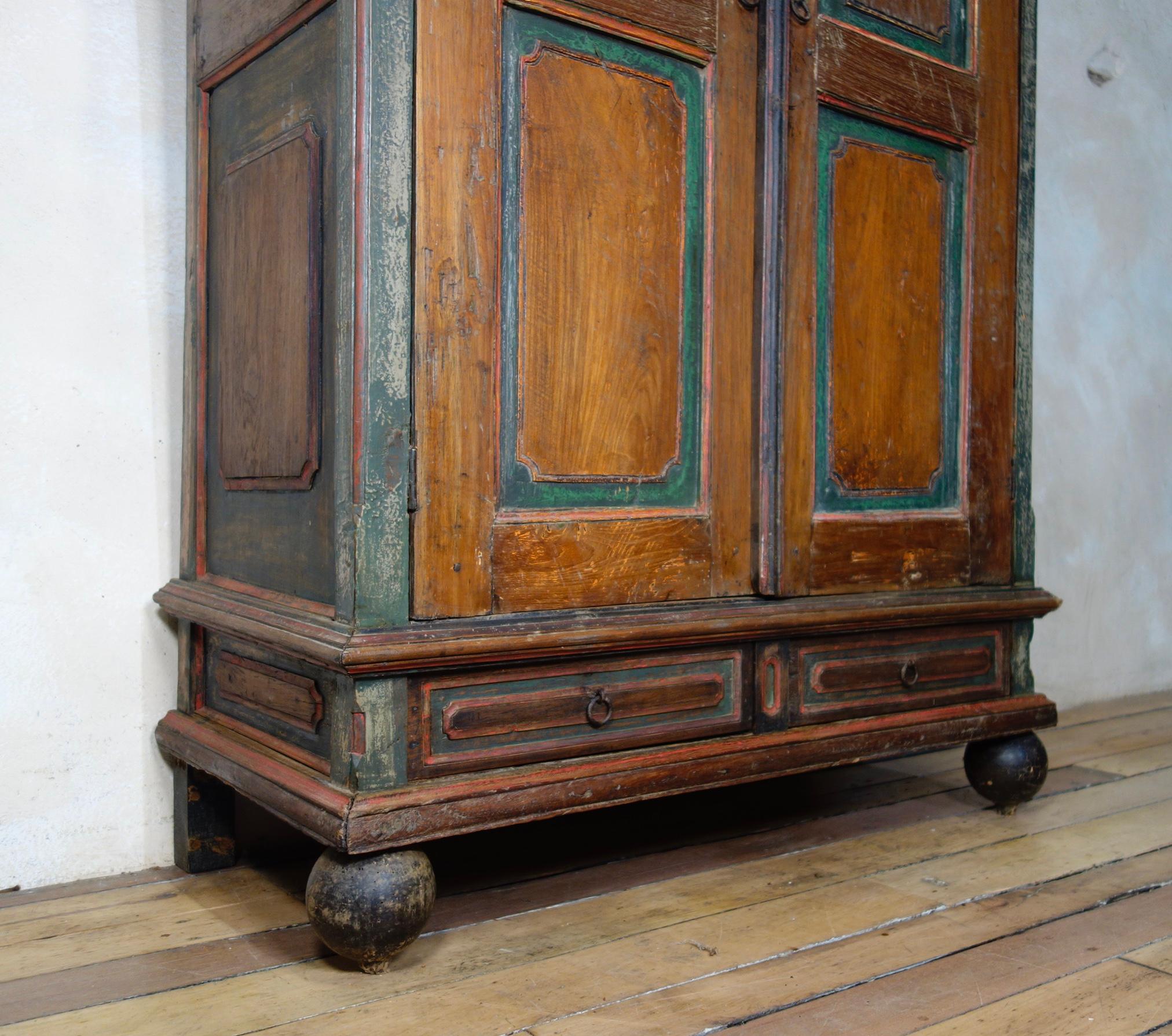 A small 19th century Folk Art painted cupboard. Displaying paneled doors with two small drawers. Raised on tulip turned ebonized feet featuring charming original paintwork throughout.

Measures: Height 154cm
Width 104cm
Depth 48cm.