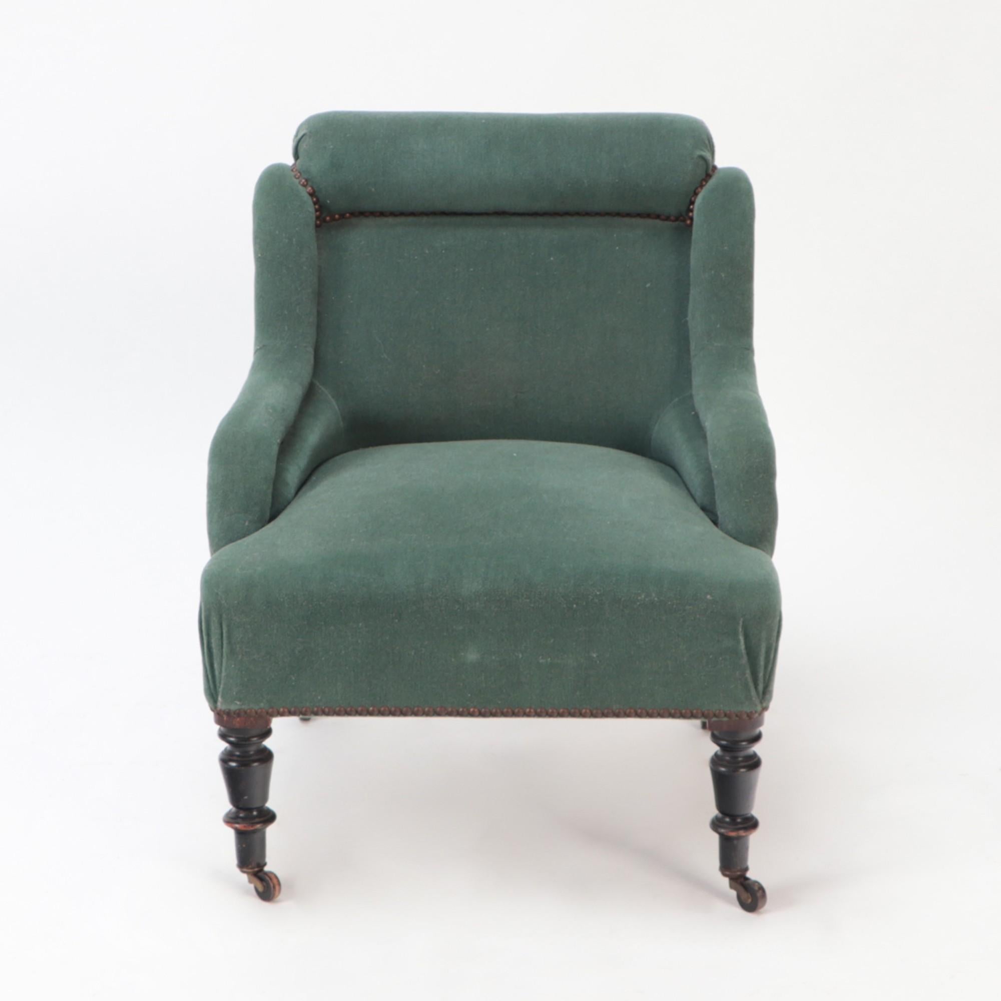 A small French Napoleon III green upholstered armchair, late 19th C. Turned legs ending in casters.