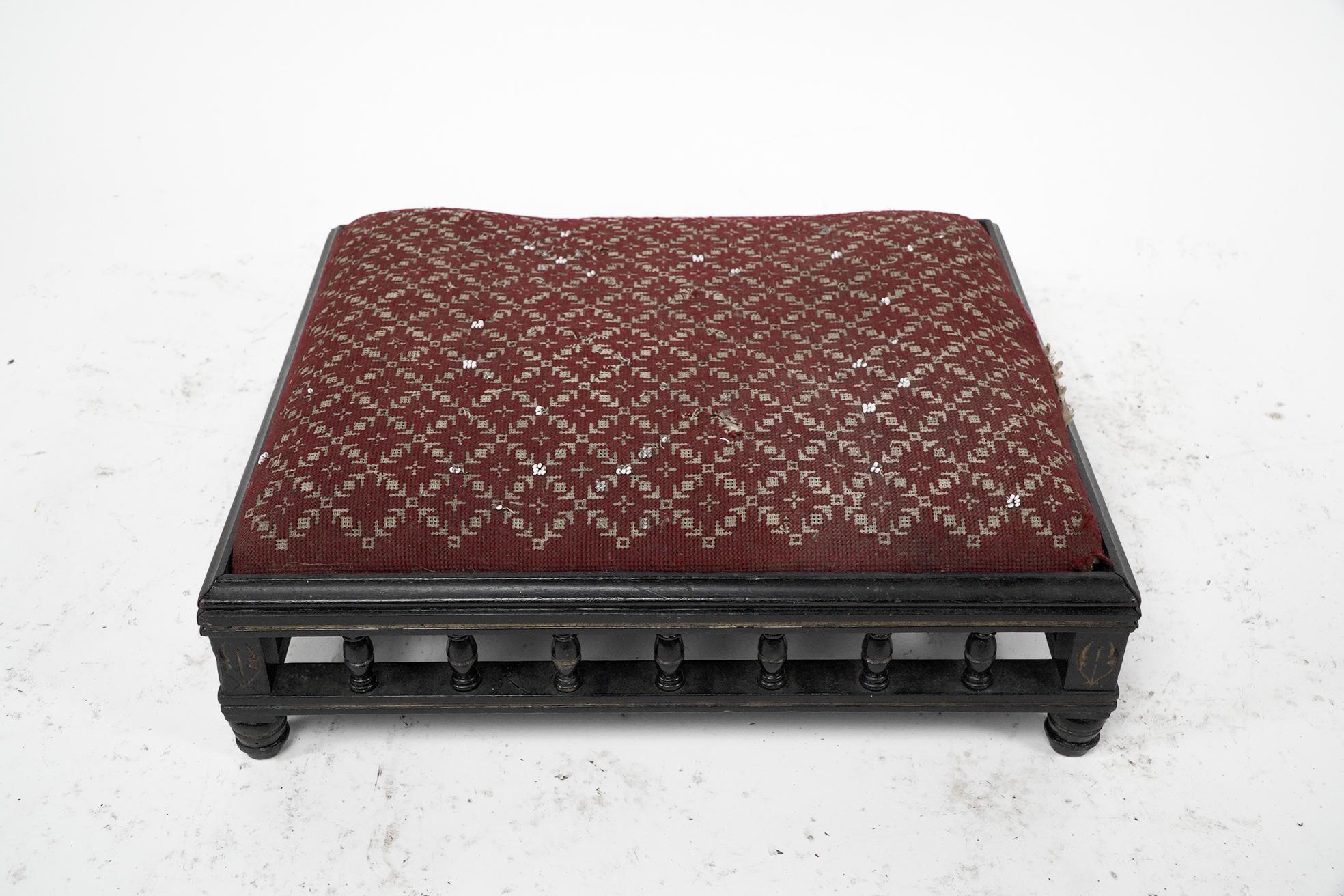 A small Aesthetic Movement ebonized foot stool, with partial gilt incised and turned decoration on stub feet.

