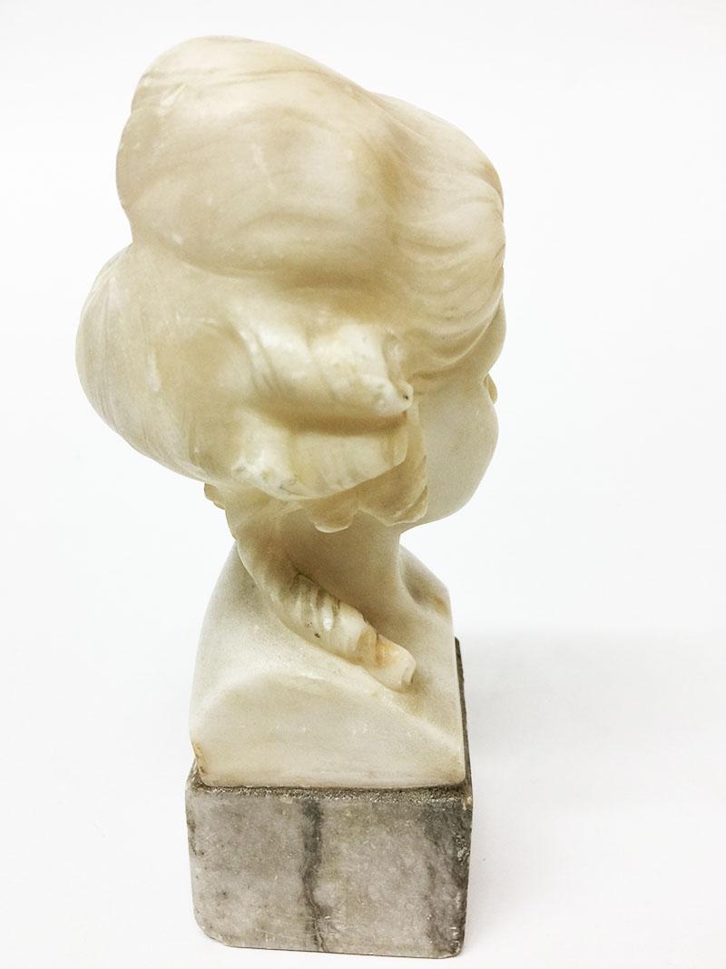 A small alabaster bust on marble base by Fritz Kochendorfer (1871-1942)
A bust of a female with curly hair, made of alabaster
Under the marble is a small medal of F. Kunst, Munchen 1891, Kochendorfer

The measurements are 17 cm high, 8 cm wide
