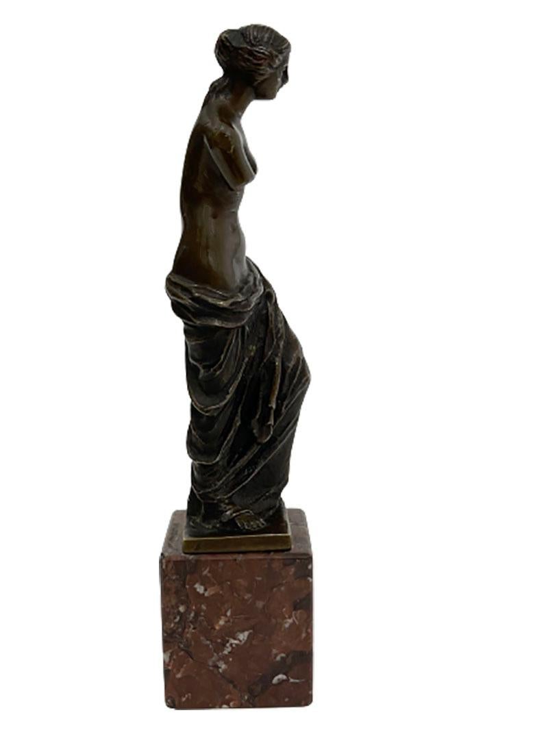 Une petite statue en bronze de la Vénus de Milo

Petite statue en bronze de la Vénus de Milo ou d'Aphrodite sur un socle en marbre.
La statue originale de la Vénus de Milo est une sculpture grecque réalisée vers 130 avant J.-C., probablement par