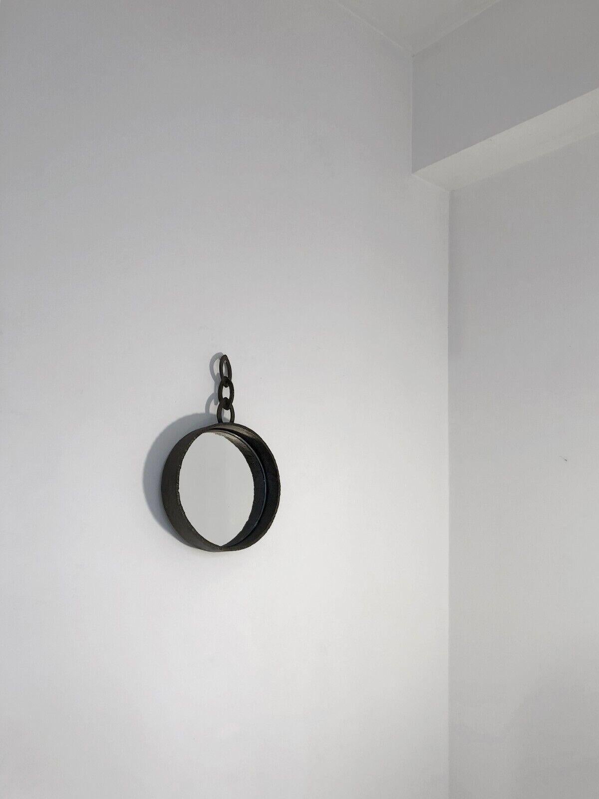 A small circular wall mirror, Modernist, Brutalist, Folk Art, Rustic-Modern, thick frame and 3-link oval chain in thick wrought iron, in the spirit of Jean Touret and Les artisans de Marolles, to be attributed, France 1960.