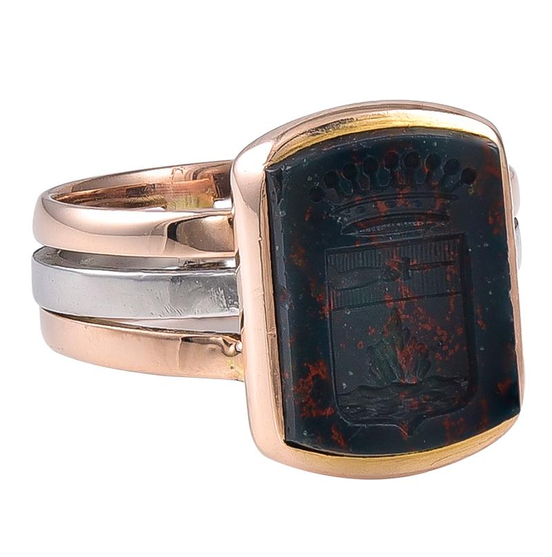 The Bloodstone Intaglio is engraved with a Naval incident within the shield and above is a 9 pointed Earls Coronet Crown. The shank comprises2 Yellowfins Gold bands and a central White Gold band, unmarked and testing for 18k.
Good pinky Ring for the