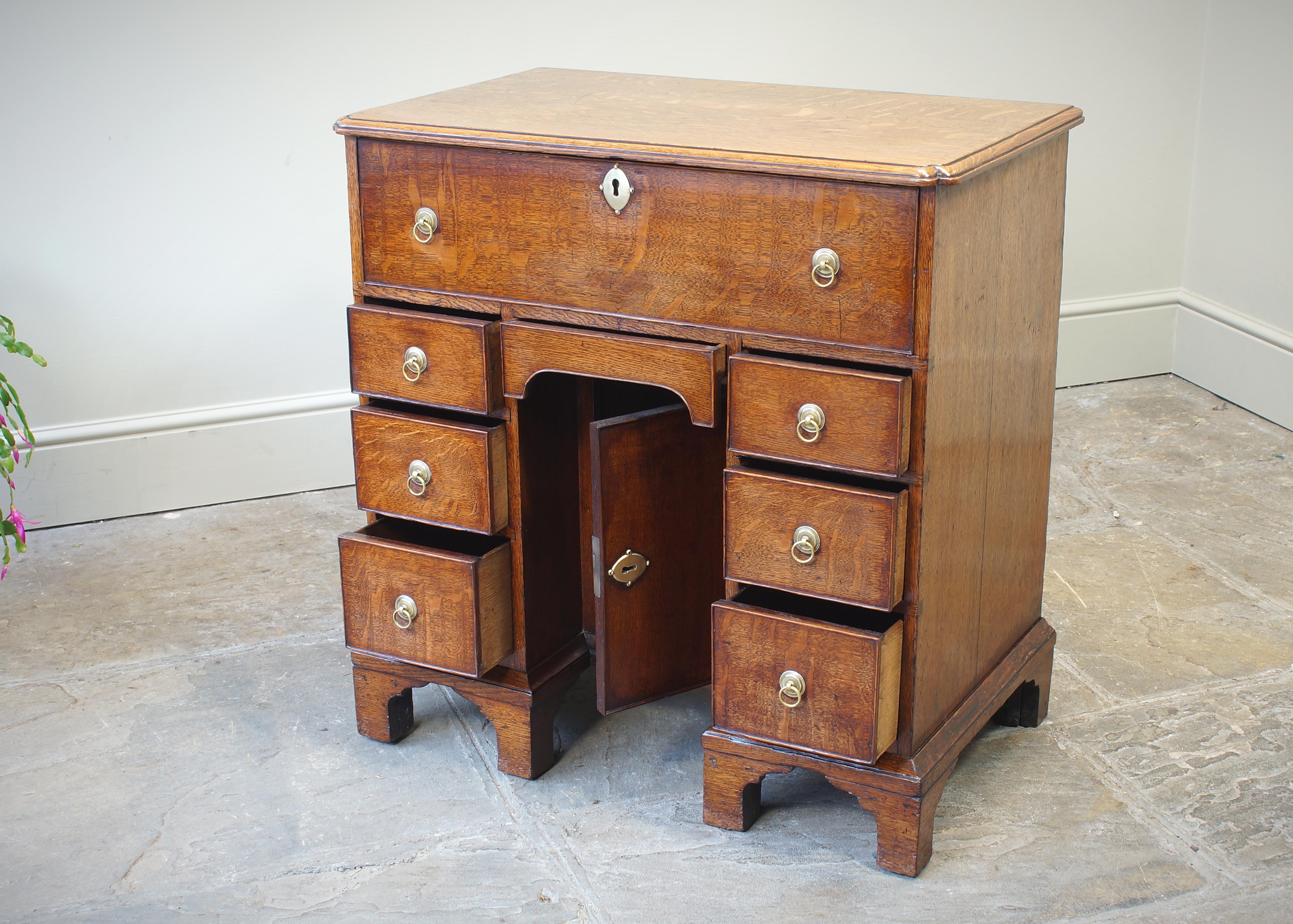 Ein kleiner georgianischer Eichen-Sekretär-Knieloch-Schreibtisch mit einer schönen hellen Honigfarbe. Der Schreibtisch ist aus hochwertigem, viertelseitig gesägtem Eichenholz gefertigt, und die Tischplatte weist ein kühnes, einspringendes Eckdetail
