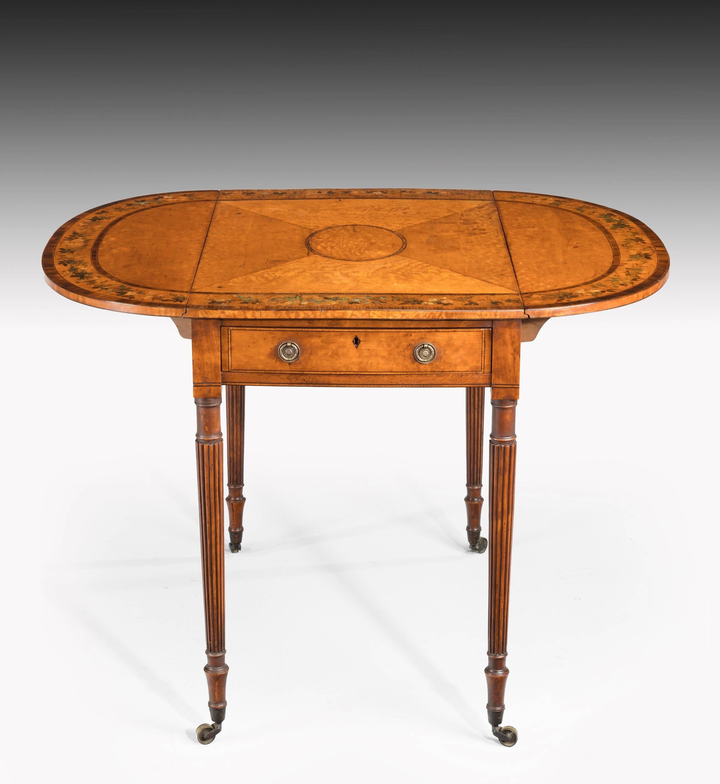 A small George III period satinwood Pembroke table. The top of quartered bookmatched timbers and oval contrasting section. Beautifully painted, broad crossbanded borders with flowers and foliage. Thin rosewood banded sections. Very finely carved