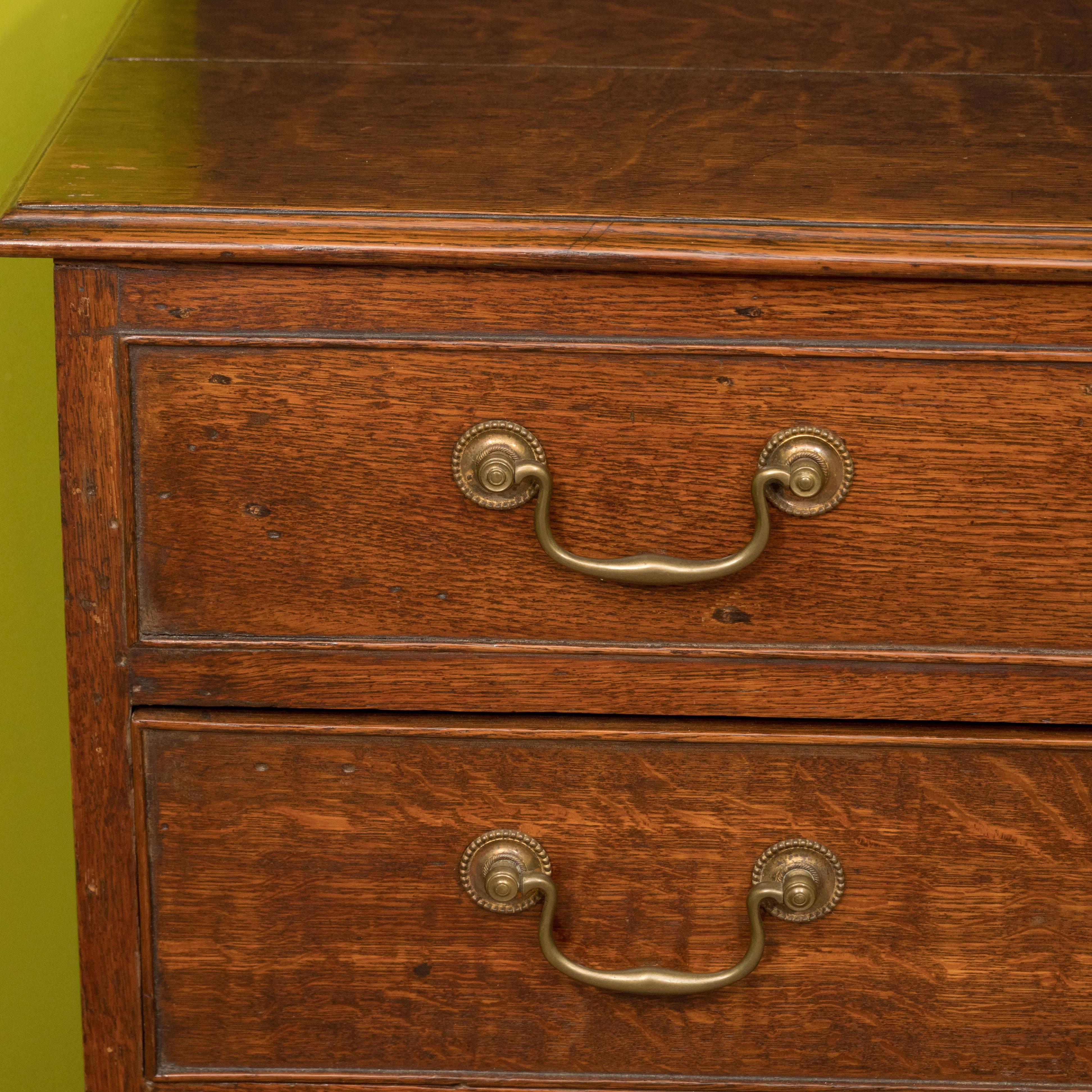 A lovely English oak chest with a hinged top and three lower drawers. The top opens to reveal a small storage compartment. The piece features brass pulls and is raised on bracket feet. The size of this chest make it quite versatile--it can serve as