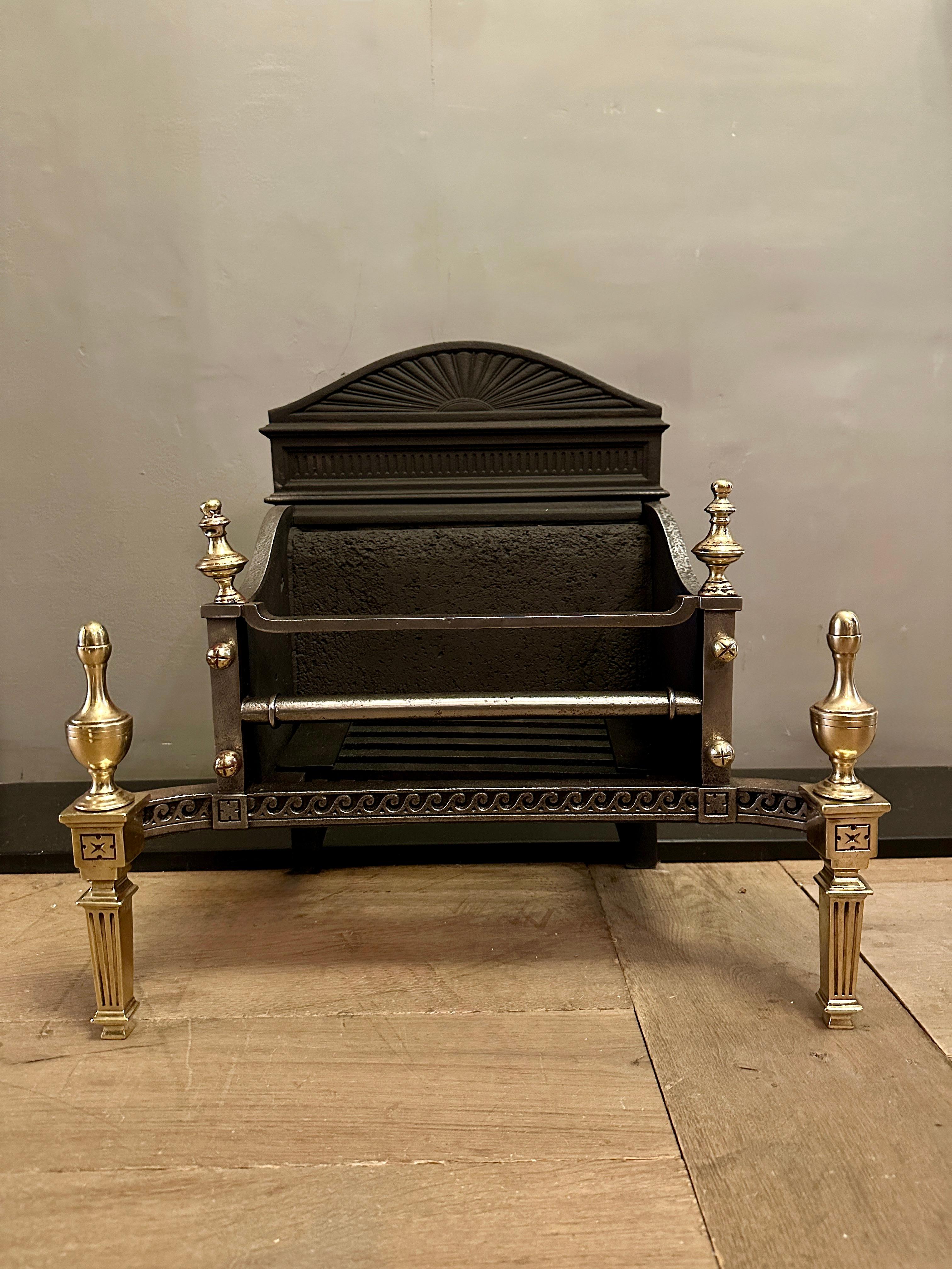 A compact Georgian style fire grate in brass and cast iron with decorative C scrolled steel apron. The back a burst of sunrise design the supports fluted pilasters with classical finials.  Although smaller in size very well decorated and Ideal for