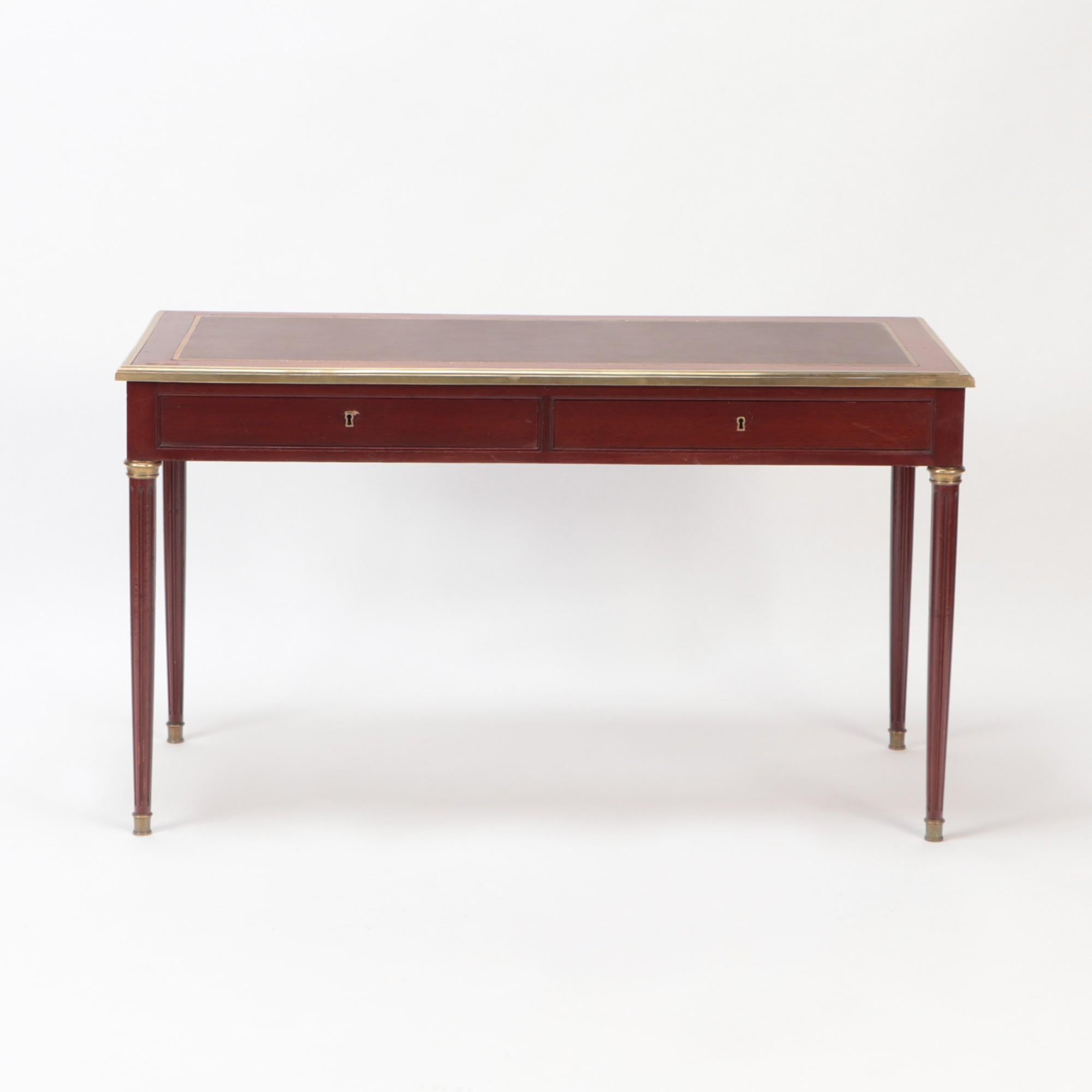 A small mahogany bronze mounted Louis XVI style writing desk C 1940. Desk has pull-out extension slides on the desk sides, each slide with embossed leather top. Square tapering legs with brass sabots.