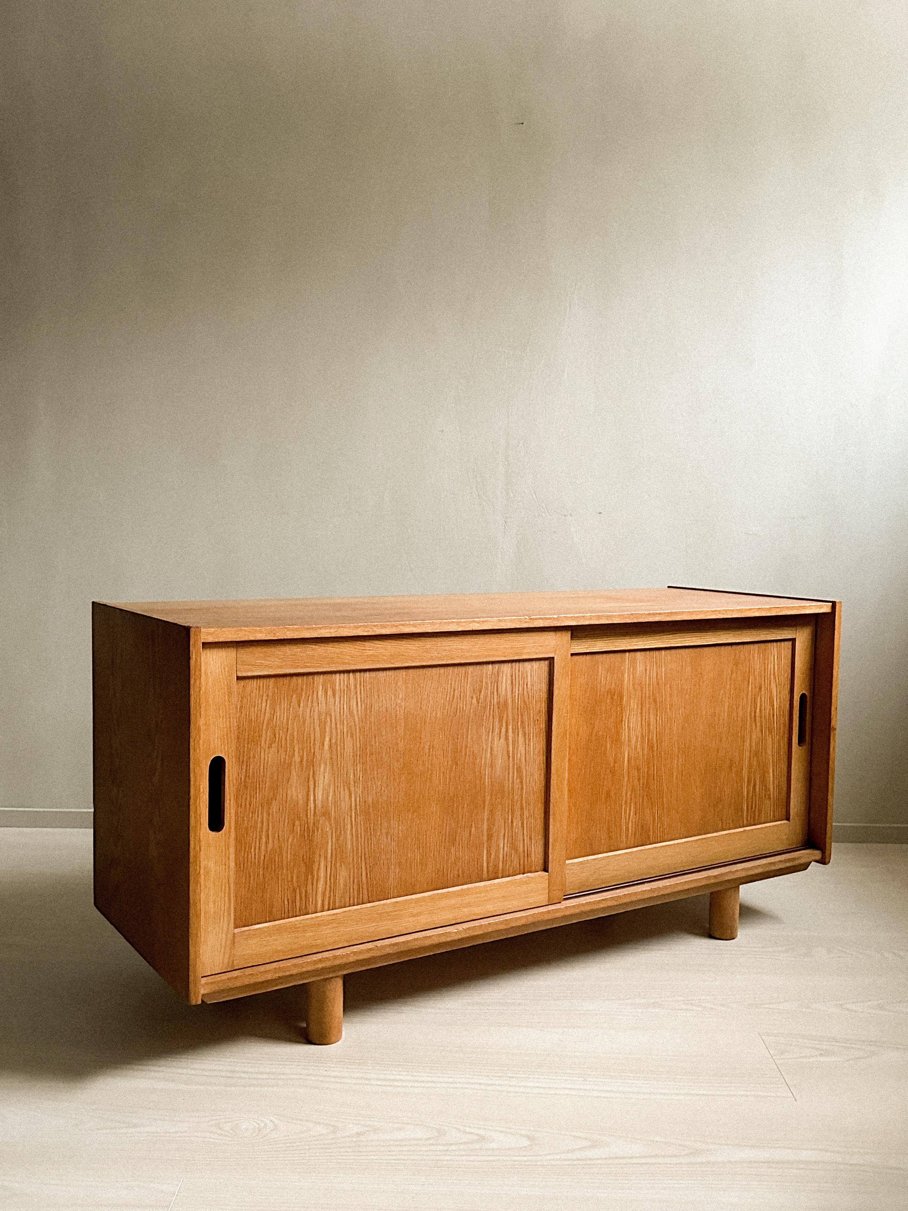 A small mid-century oak sideboard with round feet. Wear consistent with age and use. Marks, scuffs, scratches. 