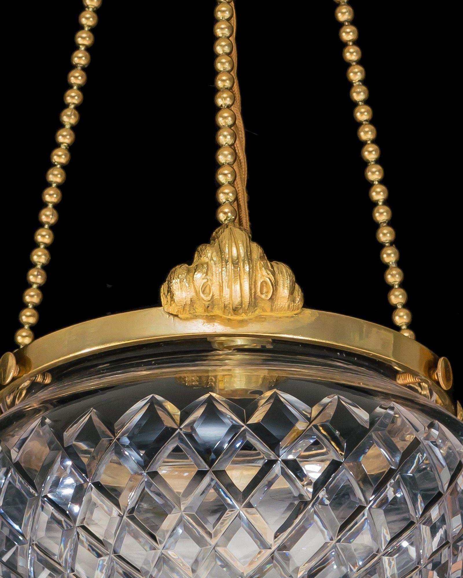 The flat diamond cut bowls mounted with gilt metalwork suspended by three ball bead chains.