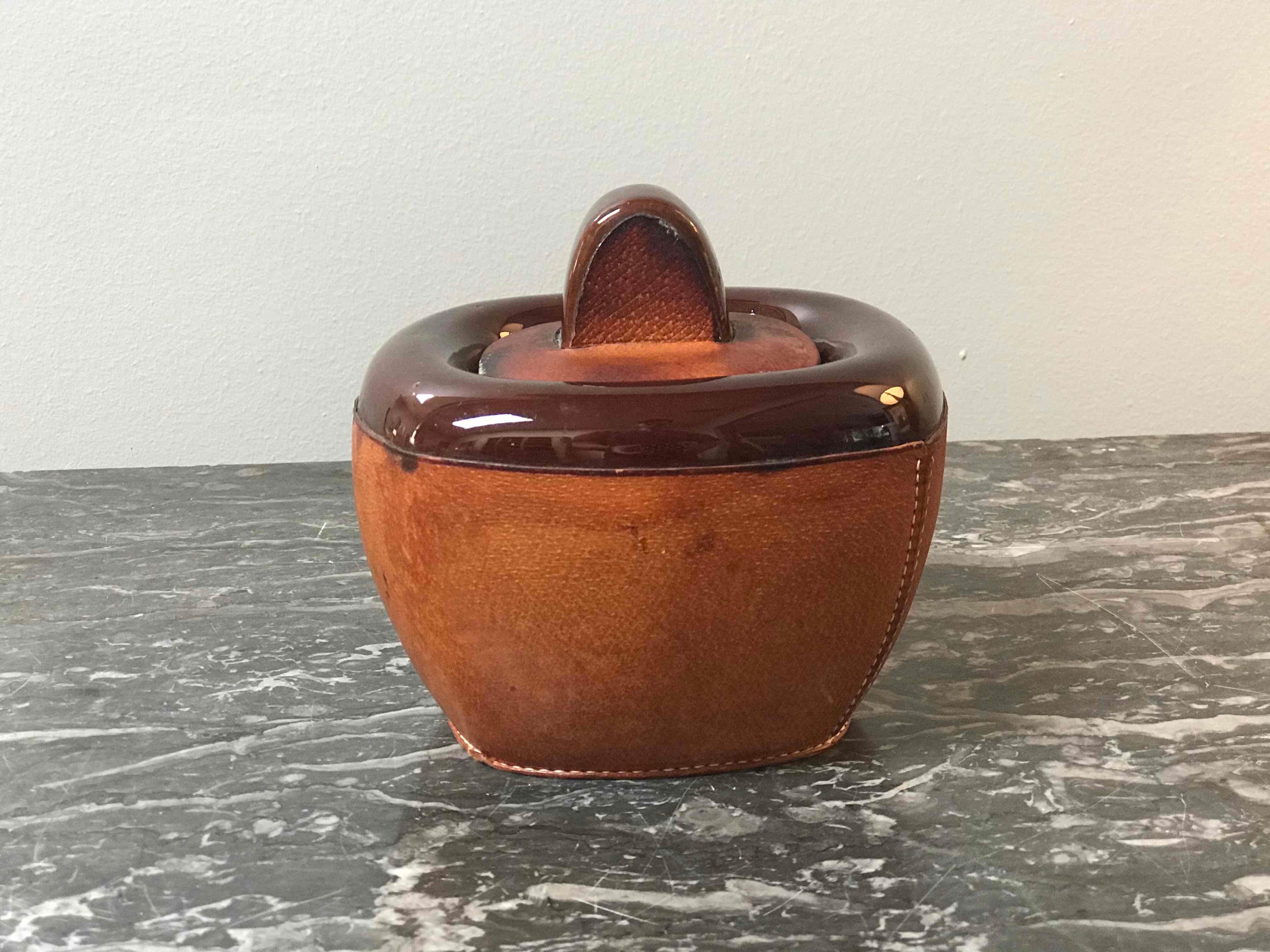 A small pottery jar with brown leather decoration and lid. Originating in France, circa 1920. 