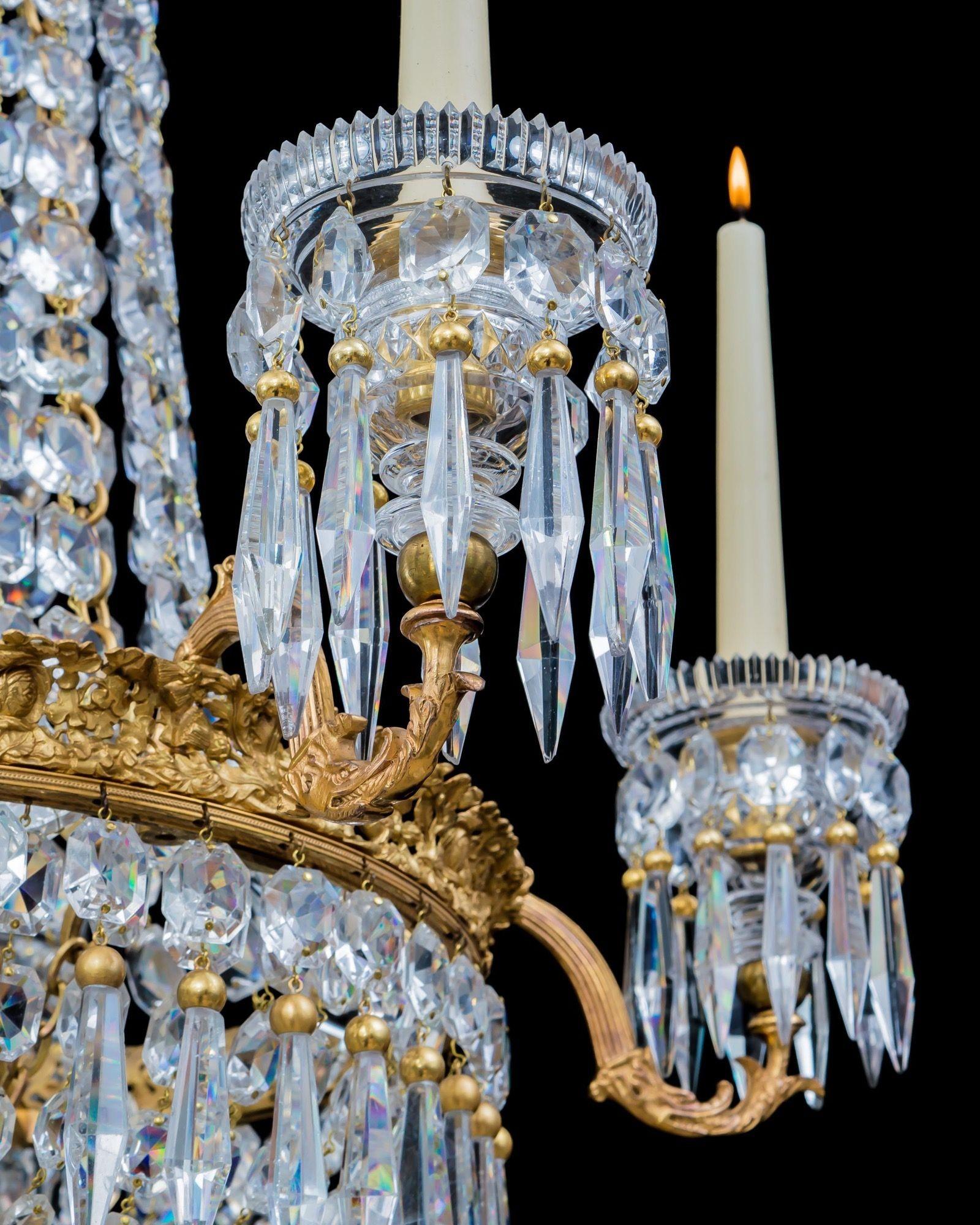 A five light ormolu mounted regency chandelier of classic tent and basket design, the ornate rose, thistle, and shamrock band issuing scroll arms of serpent form supporting drop hung candle nozzles, the chandelier hung with cascading flat back
