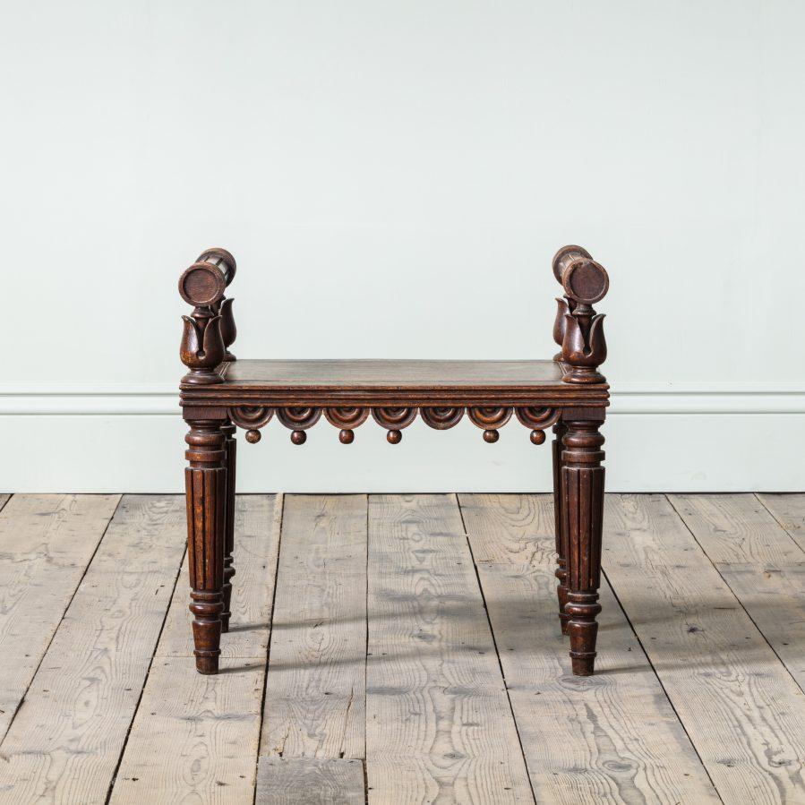 Una piccola panca da sala in Oak della Reggenza, alla maniera di Bullock

Con supporti a foglie di loto torniti, sopra un sedile pannellato con un fregio di mezzi tondi e pendenti a sfera, su gambe scanalate tornite, circa 1815.

Altezza: 60 cm, 23