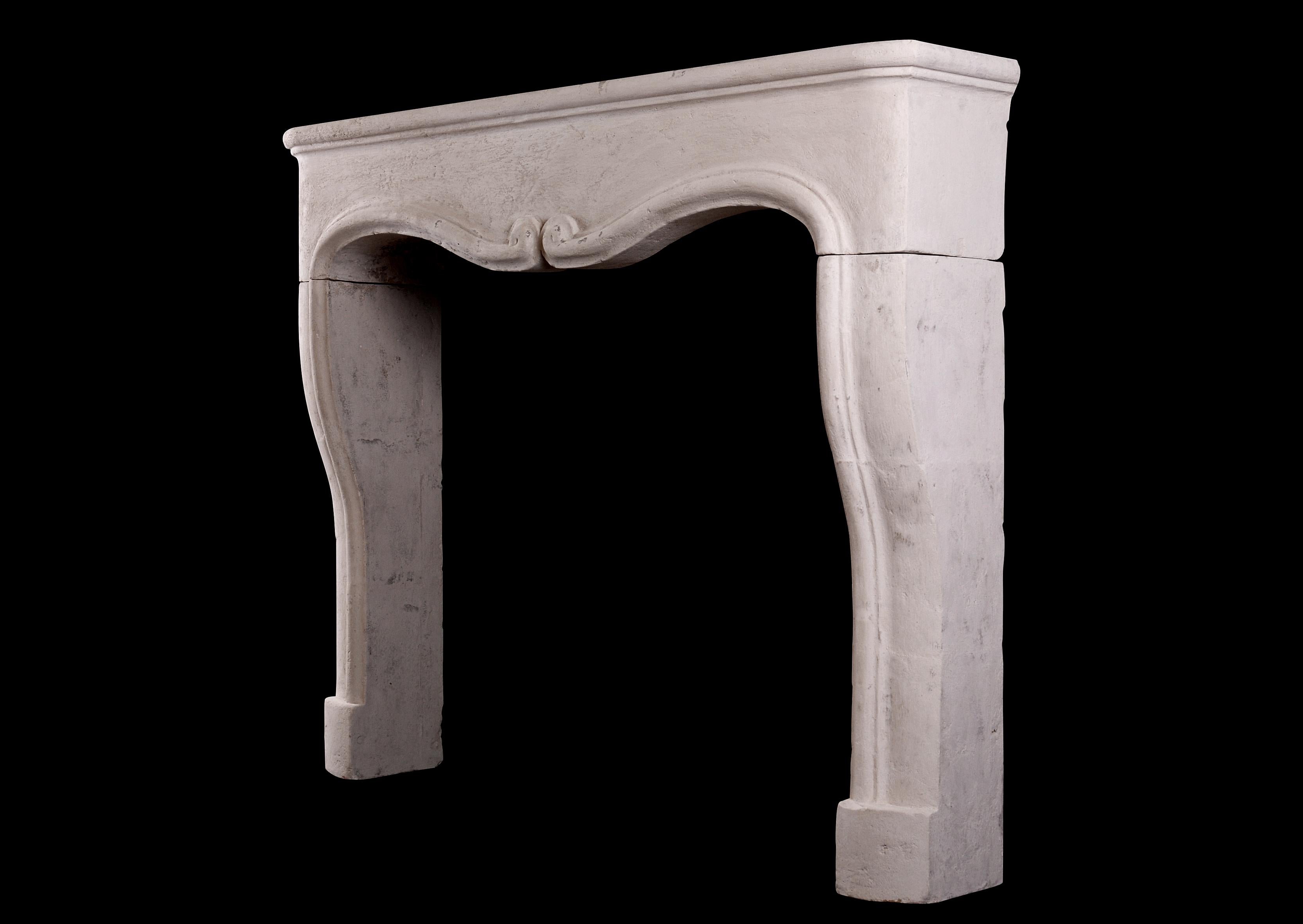A small scale, rustic French stone fireplace. The shaped jambs surmounted by elegantly scrolled frieze and shelf. 19th century. 

Measures: Shelf width: 1398 mm 55